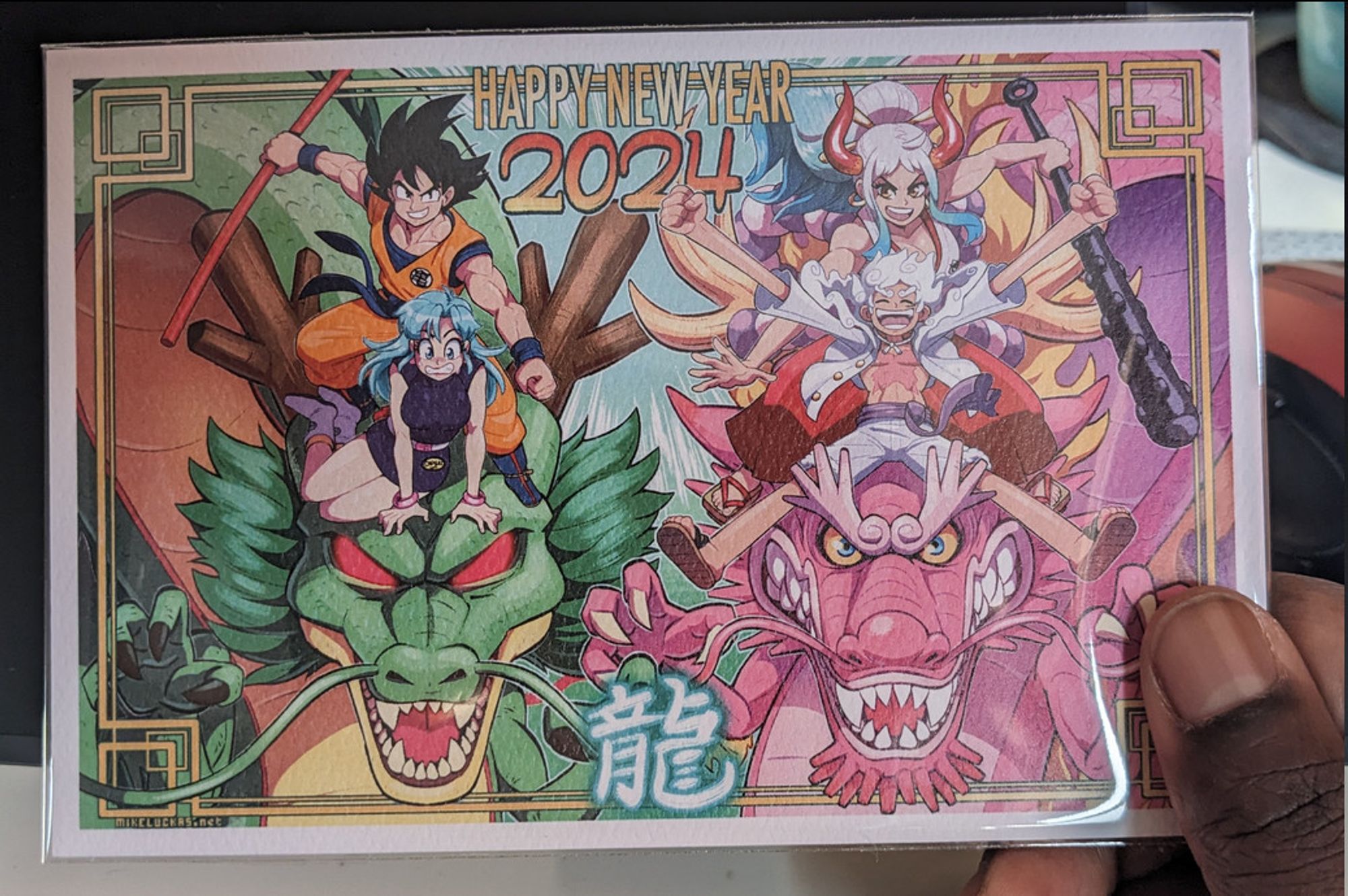 Postcard that shows an illustration of Goku, Bulma, Shenron, Yamato, Luffy (Gear 5), and Momonosuke (dragon form). It reads "Happy New Year 2024" drawn by MikeLuckas/Skullhead.