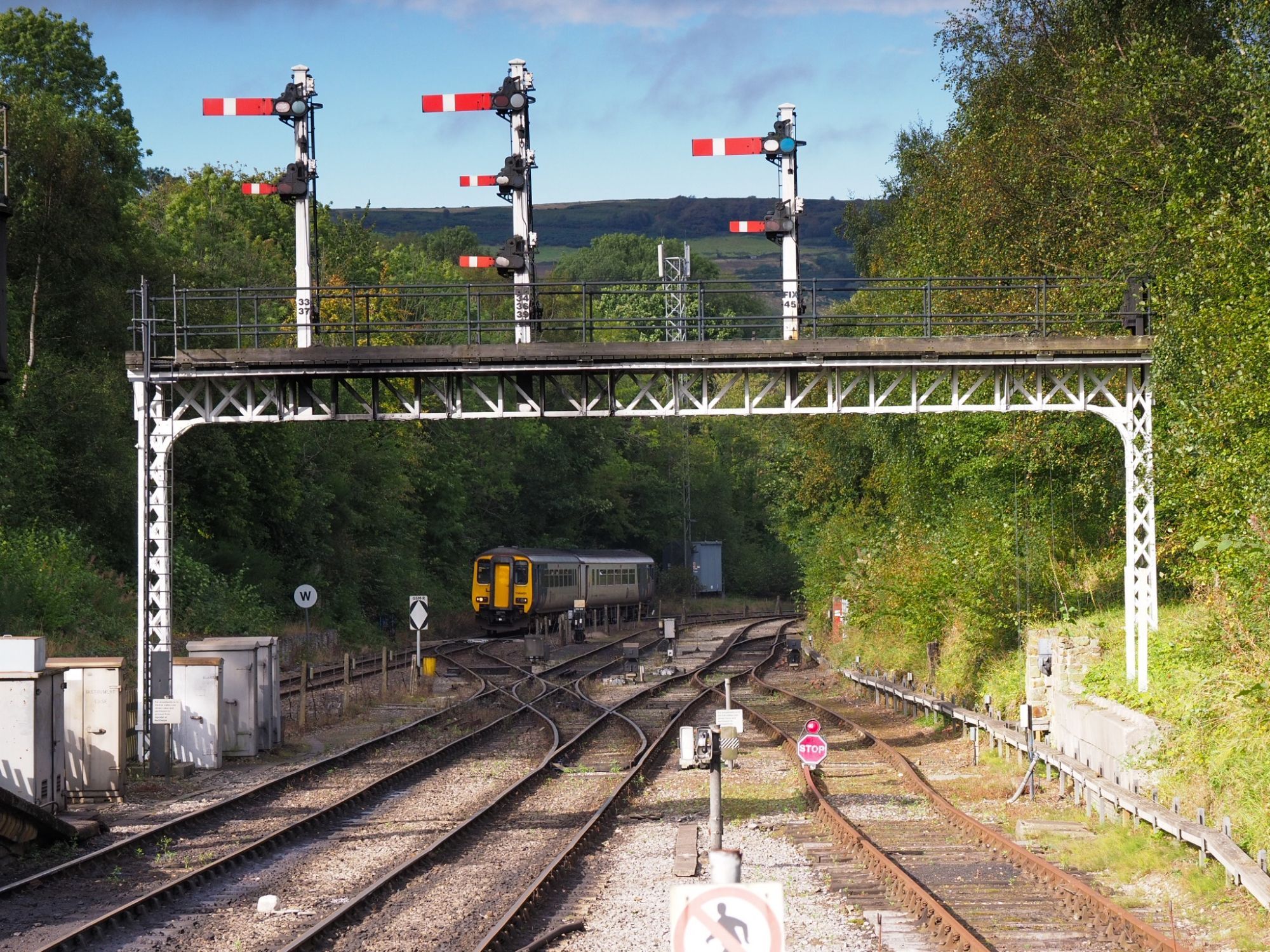 Gantry with three mechanical signals. A public Northern train is appearing behind them