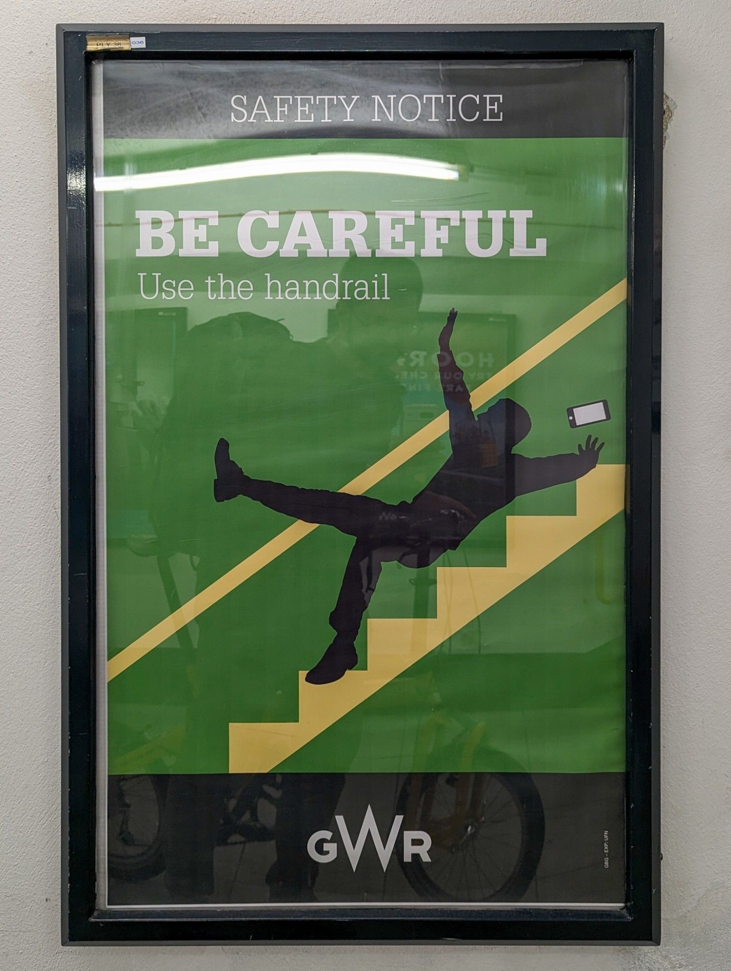 GWR poster: «Be careful, use the handrail»: Graphic of a person falling down the stairs. Green beckground.