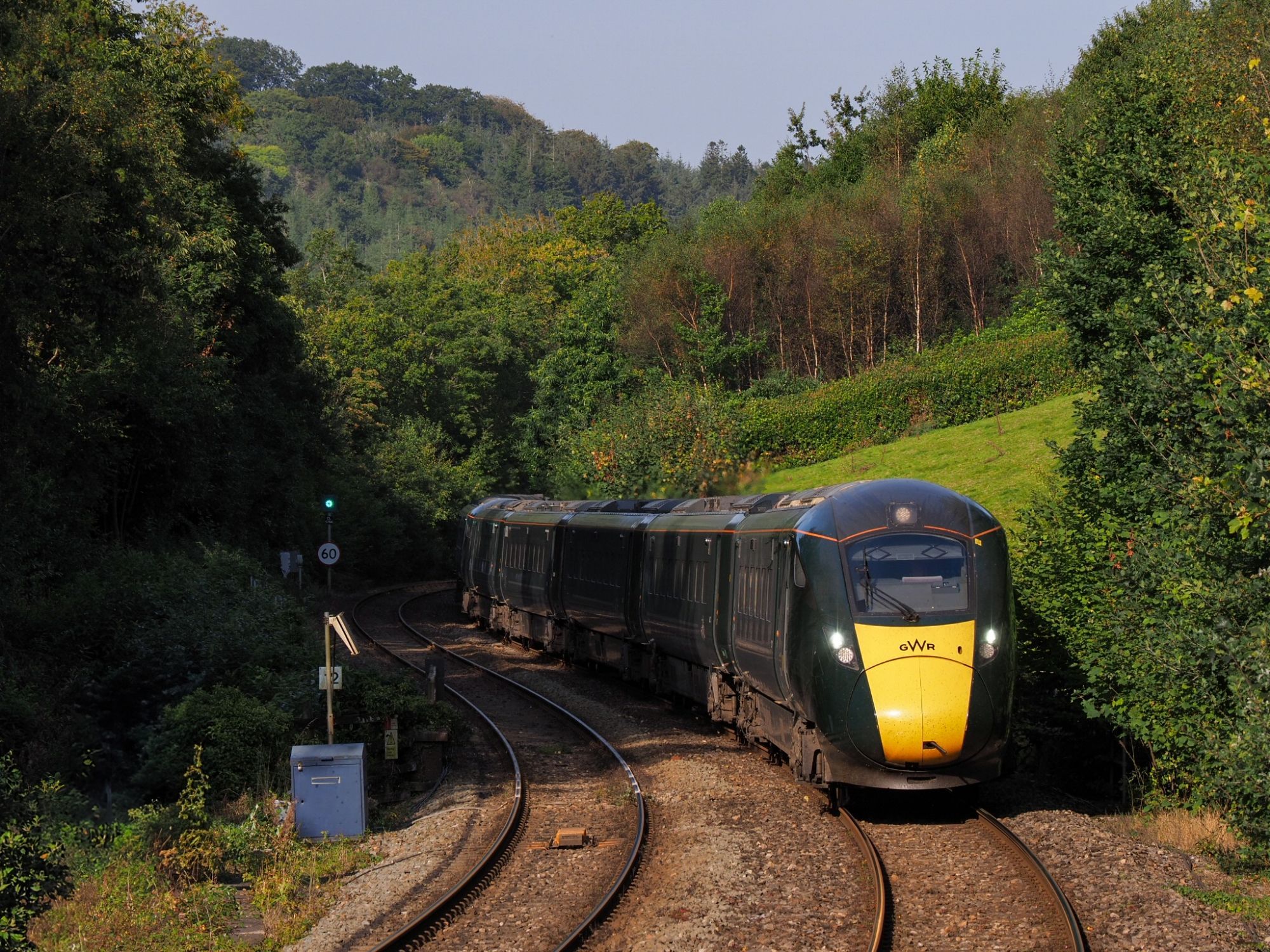 IET curving into Bodmin Parkway, the shadows of nearby trees already reach the track. (A white, new box with signalling equipment at the left side of the image has been removed with photoshop)