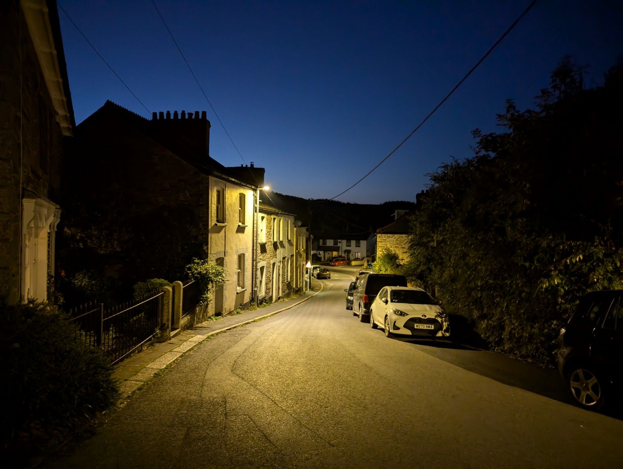 Village street with old houses in the night, illuminated by yellow street lamp light