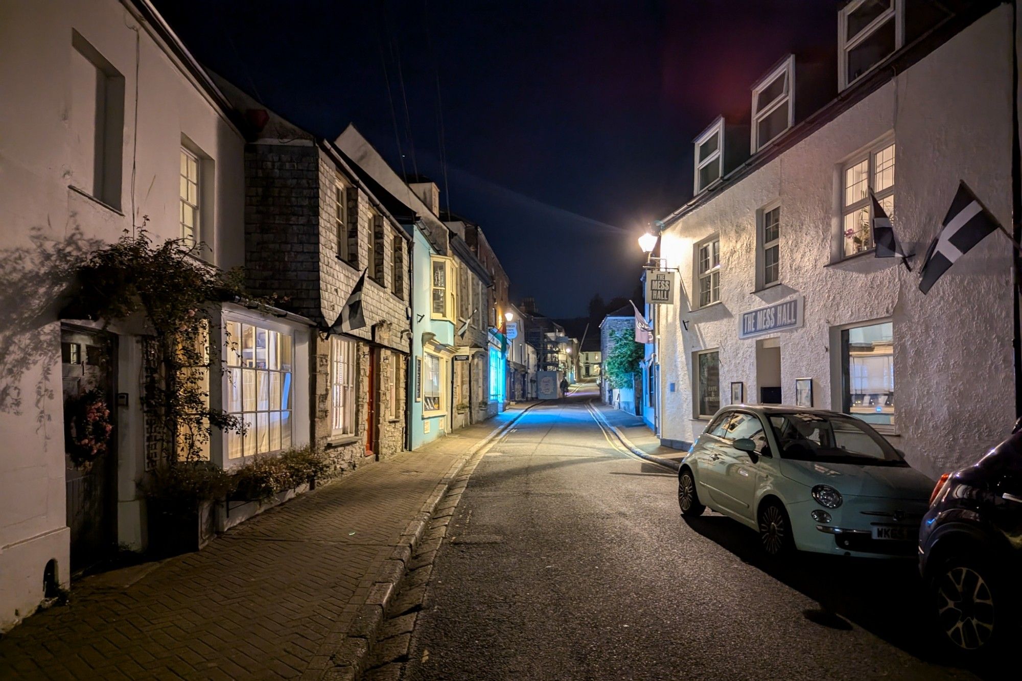 Village street at night. Old houses, one is decorated with Cornish flags.