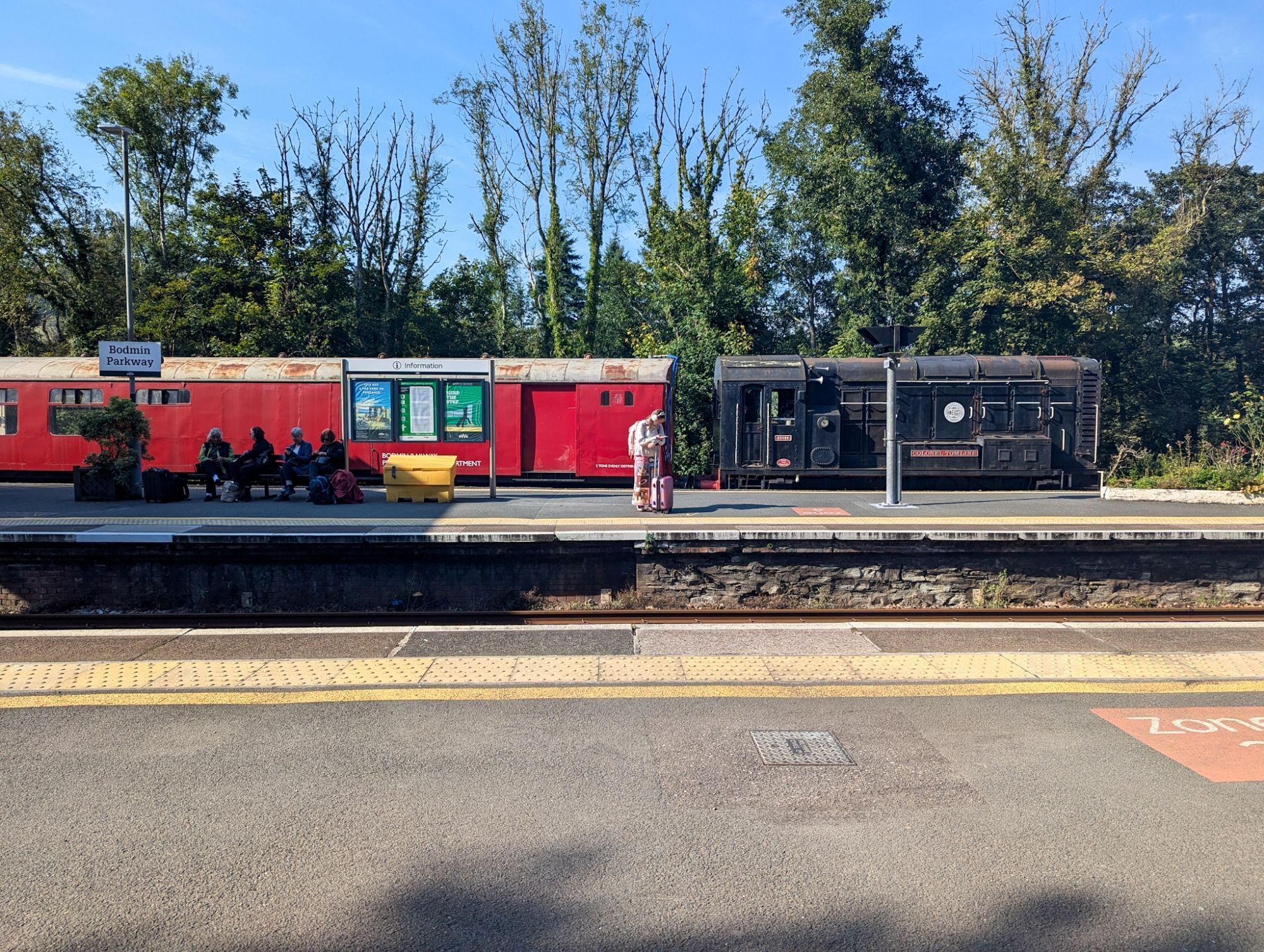 An old black, small diesel shunter pulls a red service carriage - which was part of some track works done by volunteers