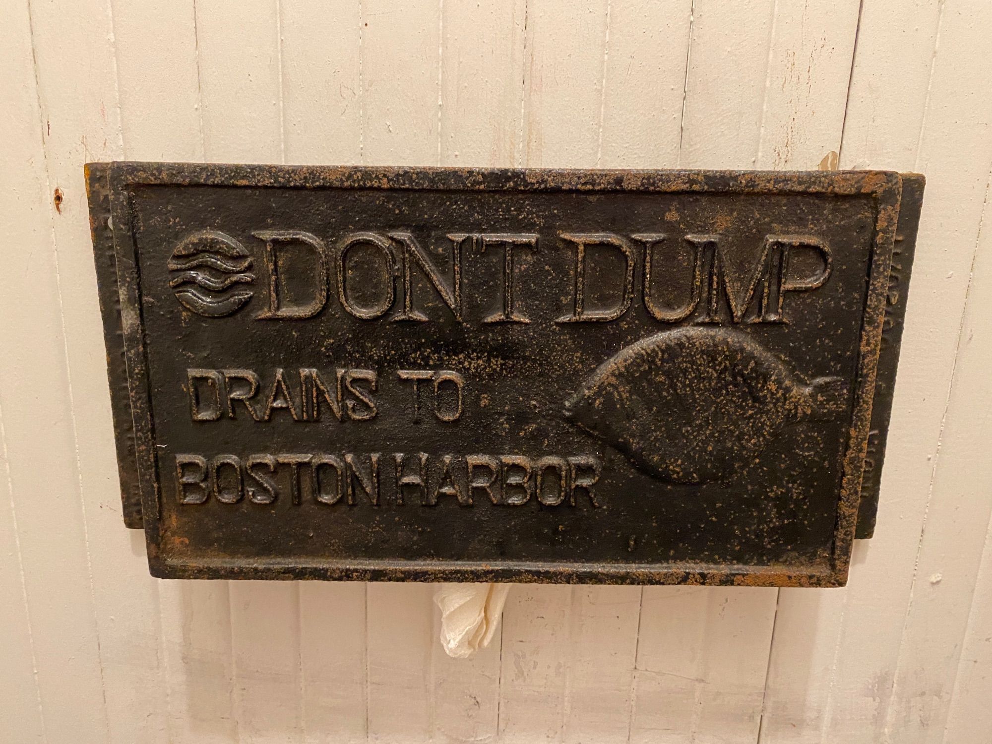 Plaque that reads “Don’t dump - drains to Boston Harbor” over a toilet in an old building next to Boston Harbor