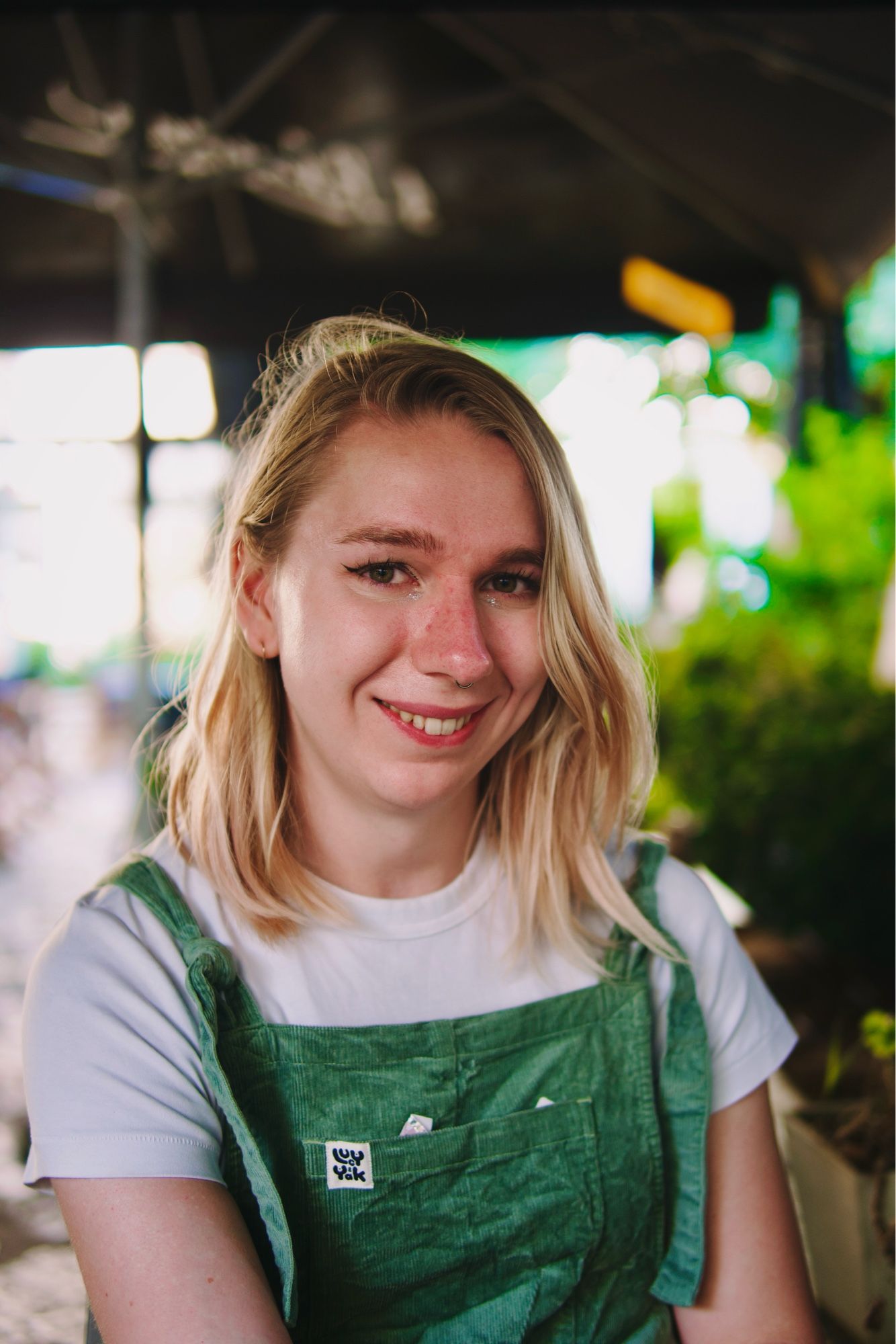 maisie smiling in portrait. she’s wearing a white t shirt and green corduroy dungarees