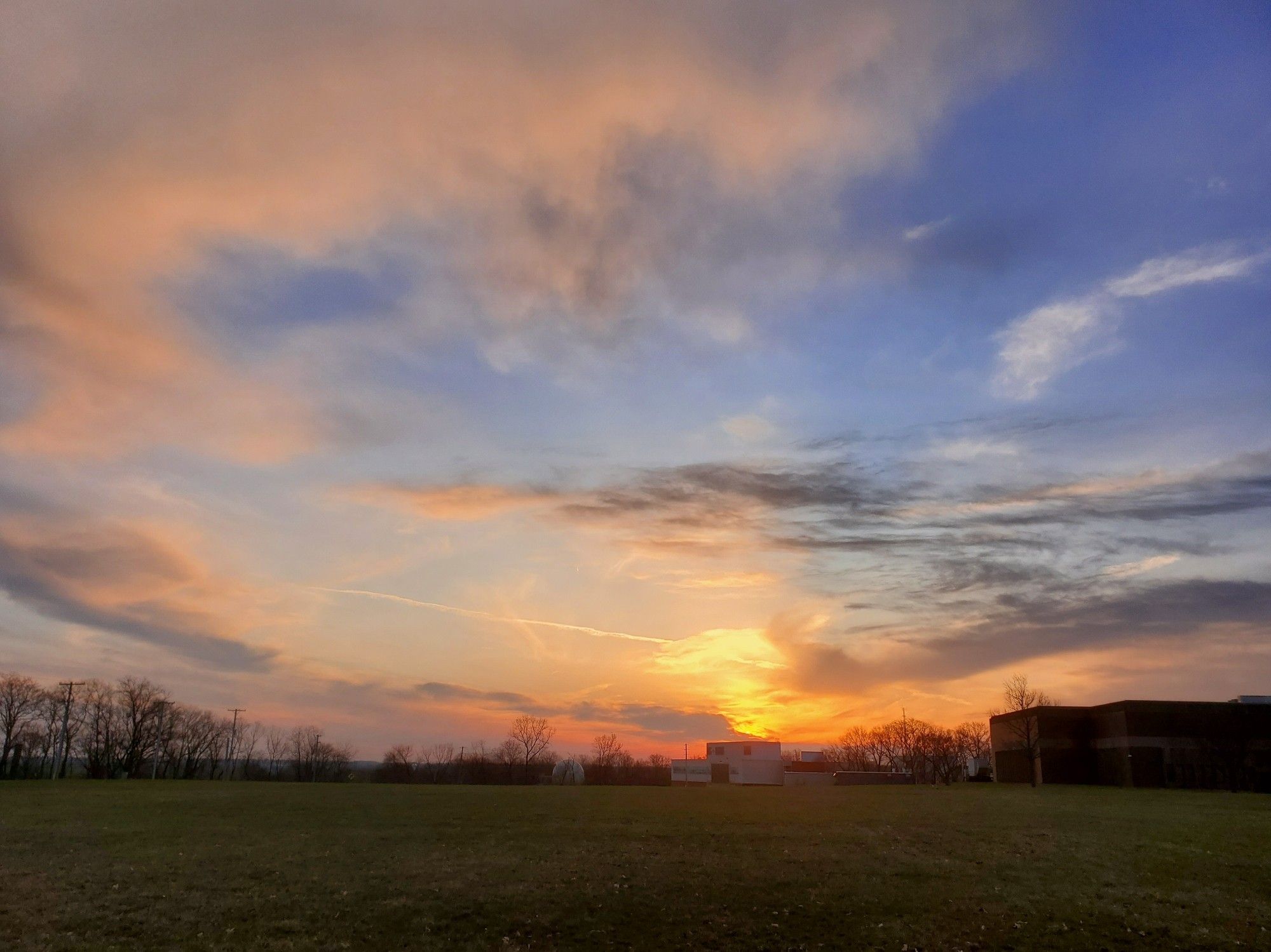 Photo of the sun rising in the east illuminating the clouds