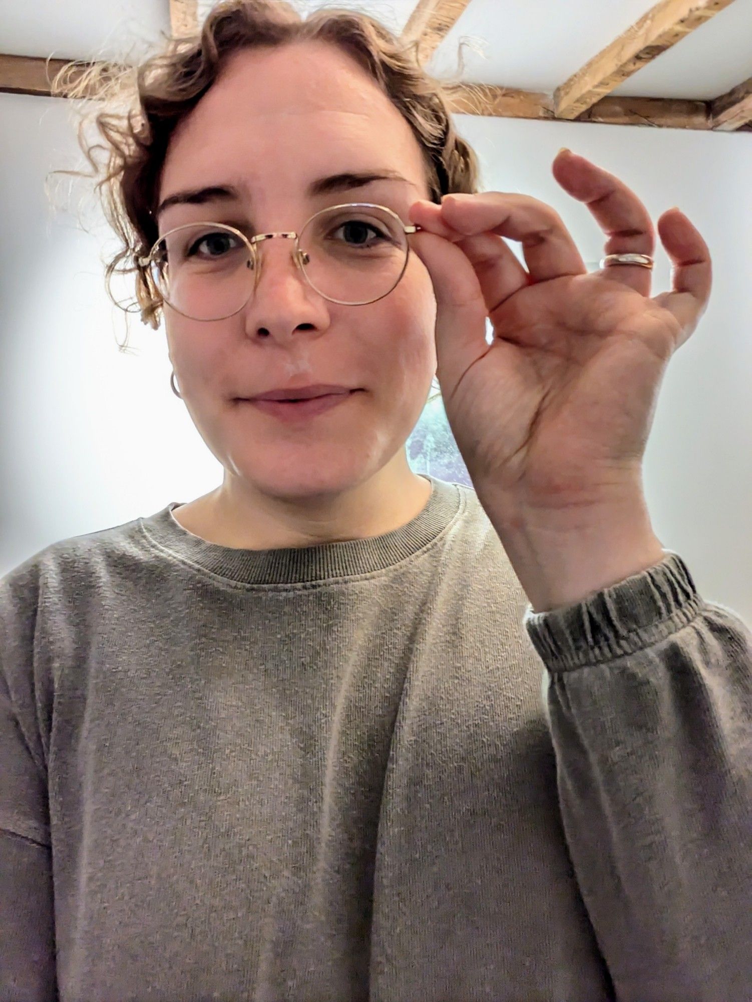 Heather wearing stolen glasses with round, thin gold wire frames and coyly smiling at the camera