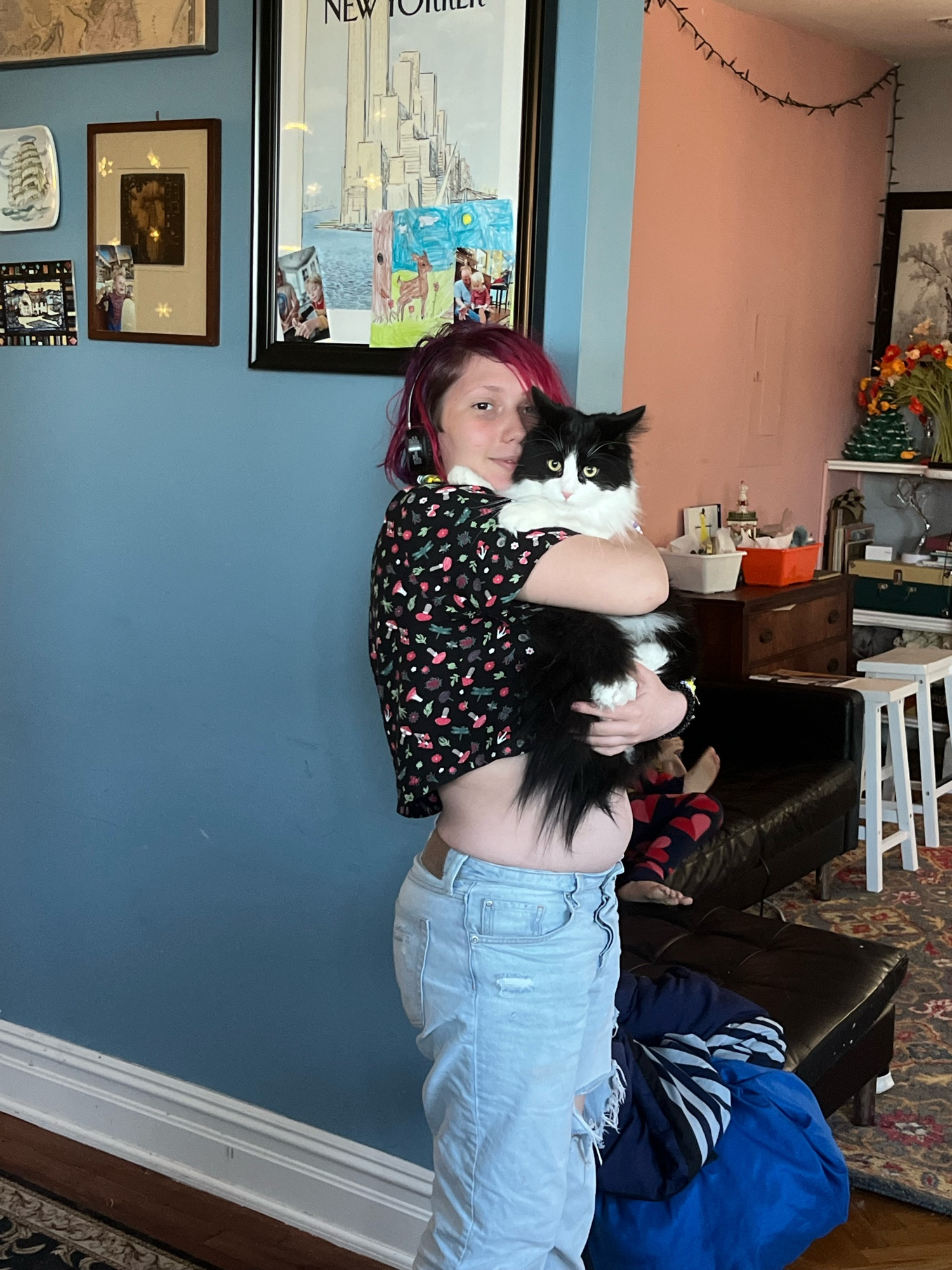 Magenta haired teen holding a black and white long haired cat 