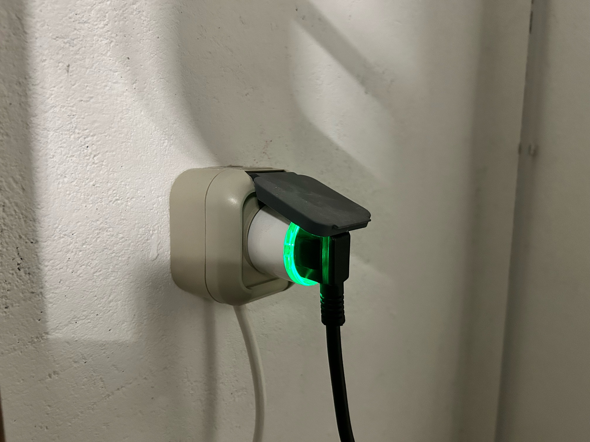 Ein weißer, smarter Zwischenstecker „Shelly Plus Plug S“ in einer Aufputzsteckdose