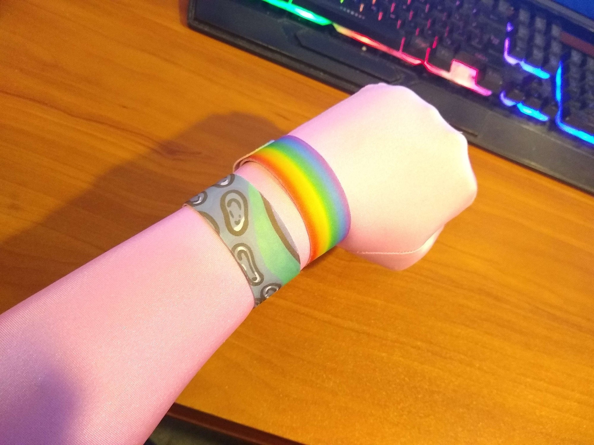 2 Slap bracelets on a wrist, one is The Pride Ranibow the other a Tentacle pattern.