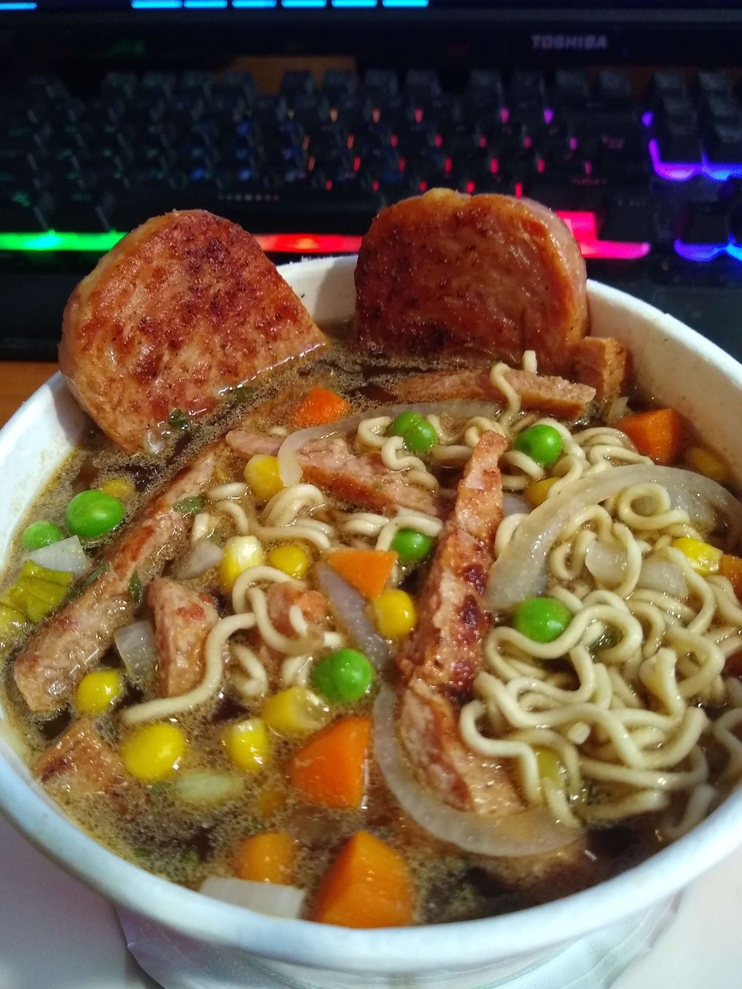 A Bowl of Instant Ramen with Fried Space, Onions, Peas and Carrots and corn added.