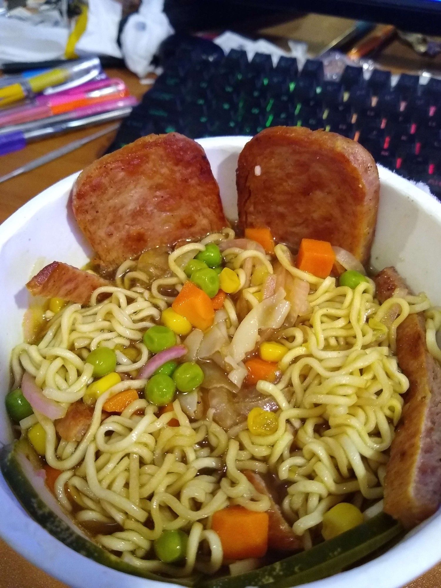 A Bowl of Instant Ramen with Fried Space, Onions, Peas and Carrots and corn added.