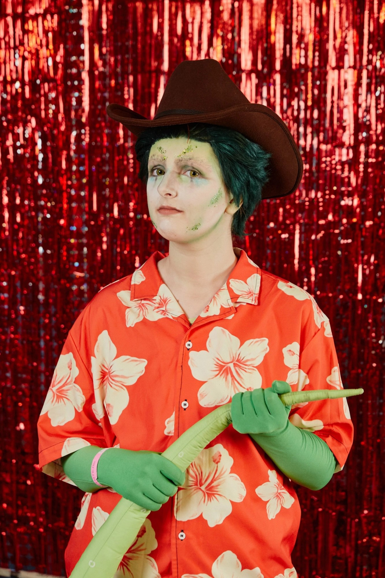 Jay as Rango wearing his red Hawaiian shirt and cowboy hat holding his tail looking at the camera in front of a red sparky background