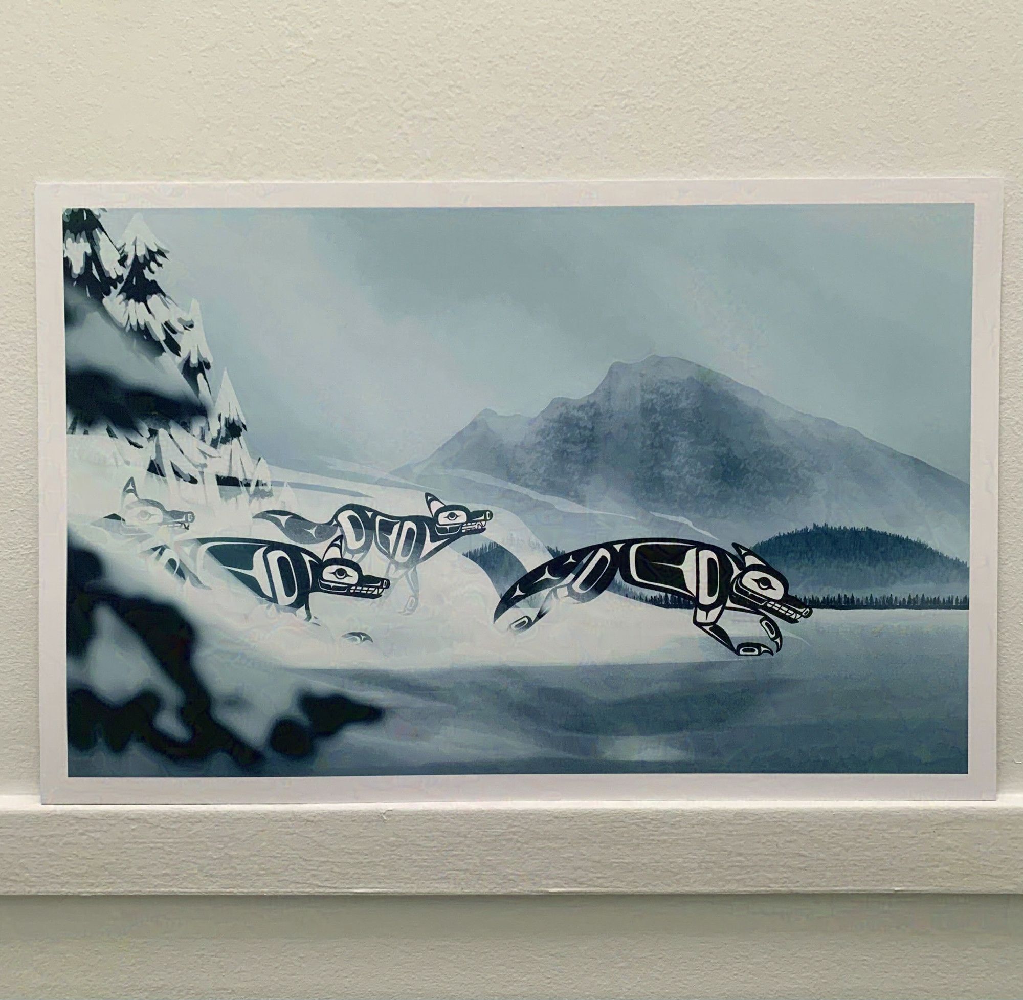 An art print of a semi-rendered illustration of formline wolves running across a foggy, snowy lake, with hills and mountains in the distance.