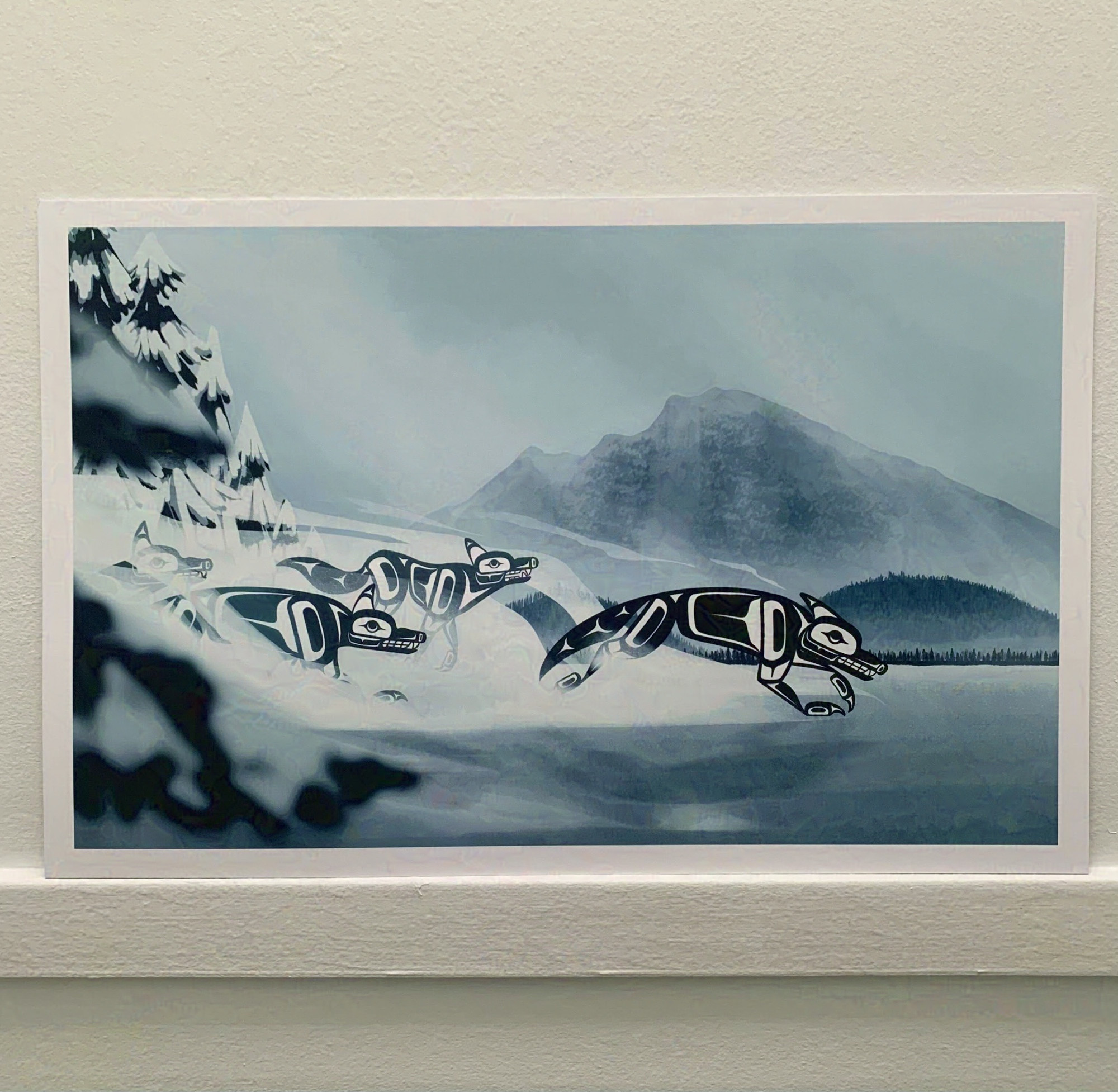 A print of an illustration of a foggy frozen lake. Formline wolves are running across it and out of the fog.