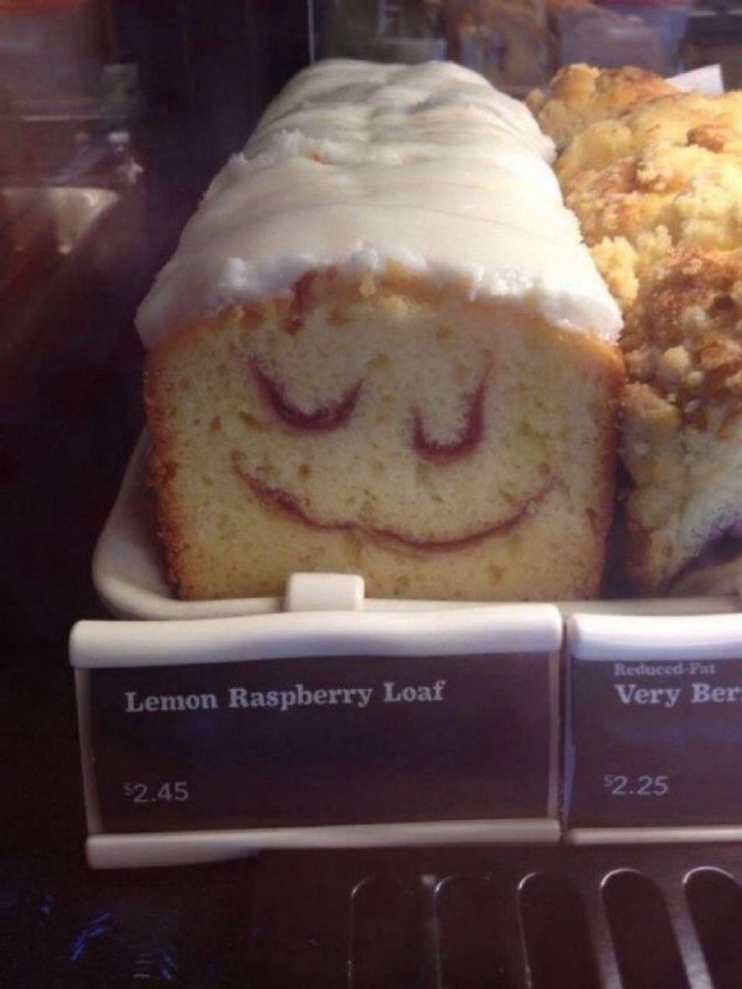 A frosted Leon raspberry loaf, sliced, looks like a sleepy cartoon face