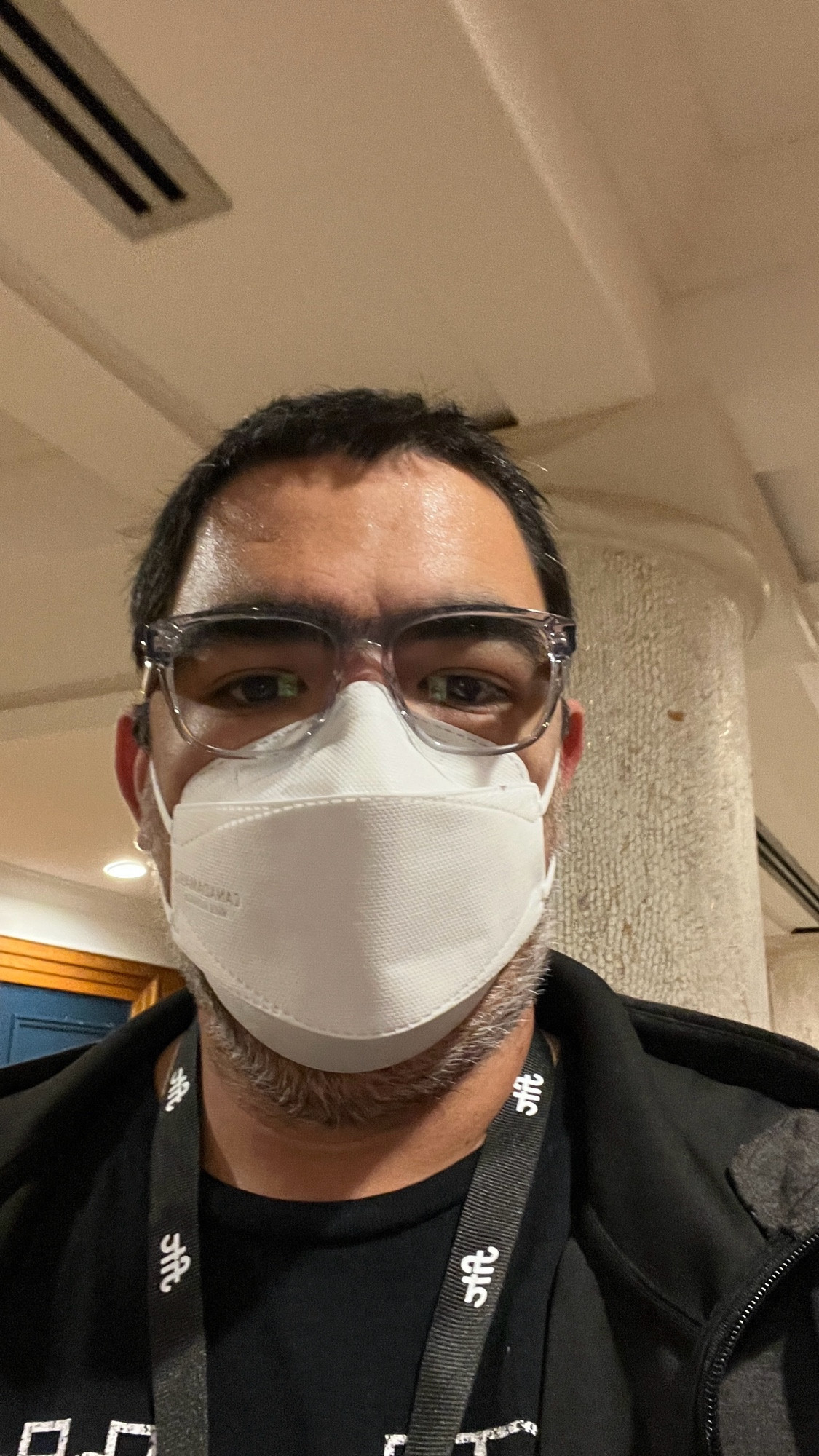 Selfie wearing a black shirt, dark light jacket, glasses and a mask