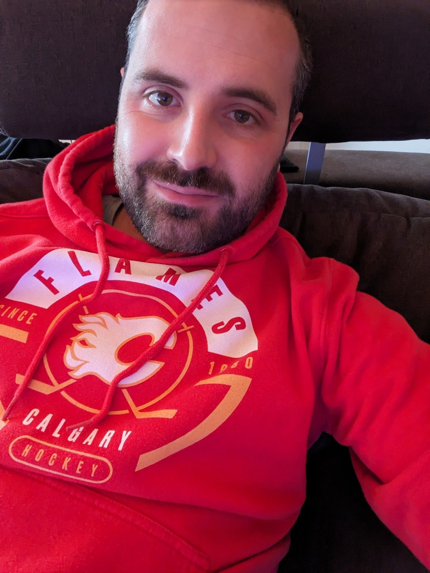 Selfie von mir, entspannt auf dem Sofa. Ich trage einen Hoodie der kanadischen Eishockey-Mannschaft Calgary Flames.