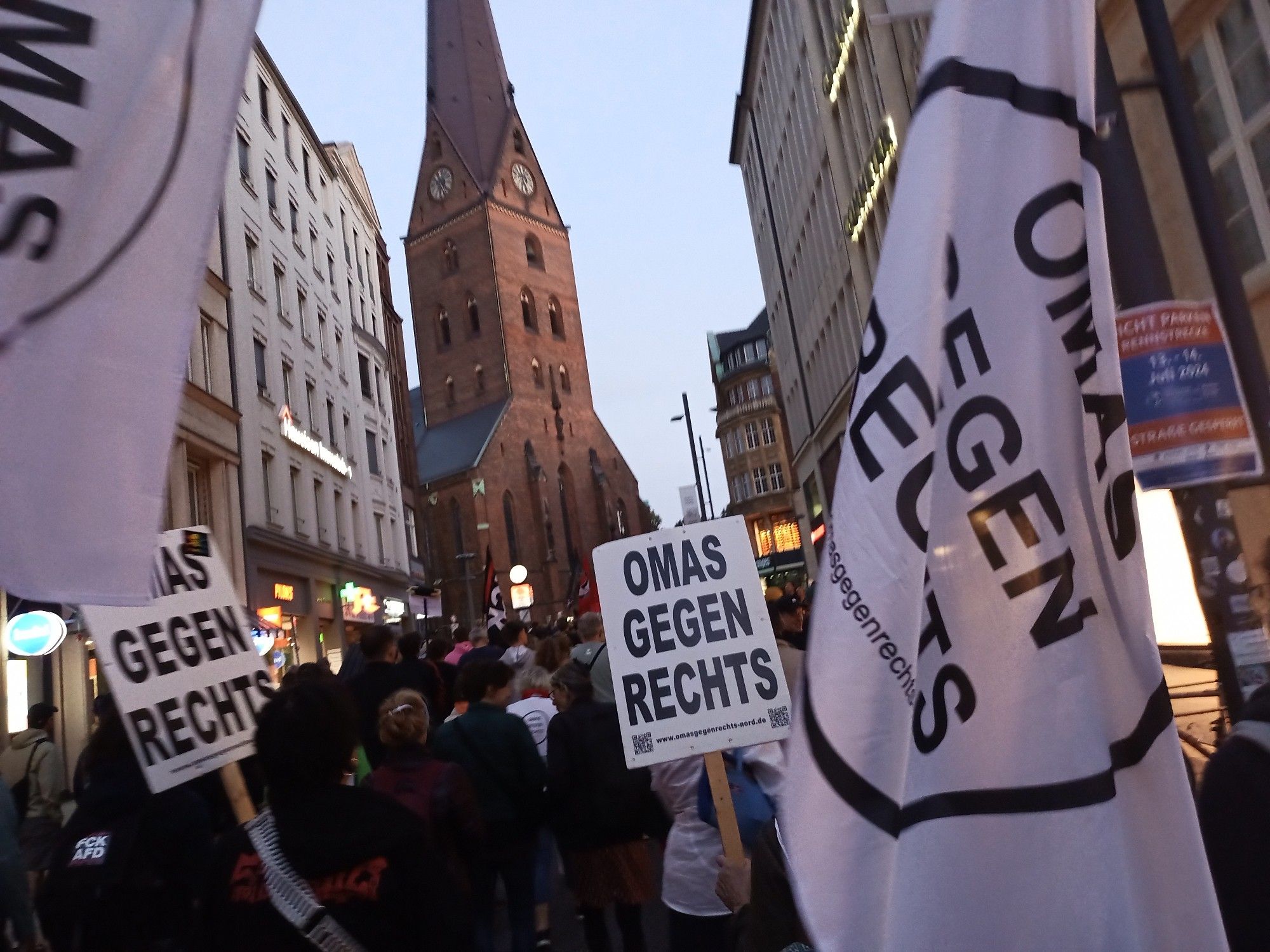 Blick in die Straße vor der Petrikirche, davor Schilder und Fahnen der OMAS