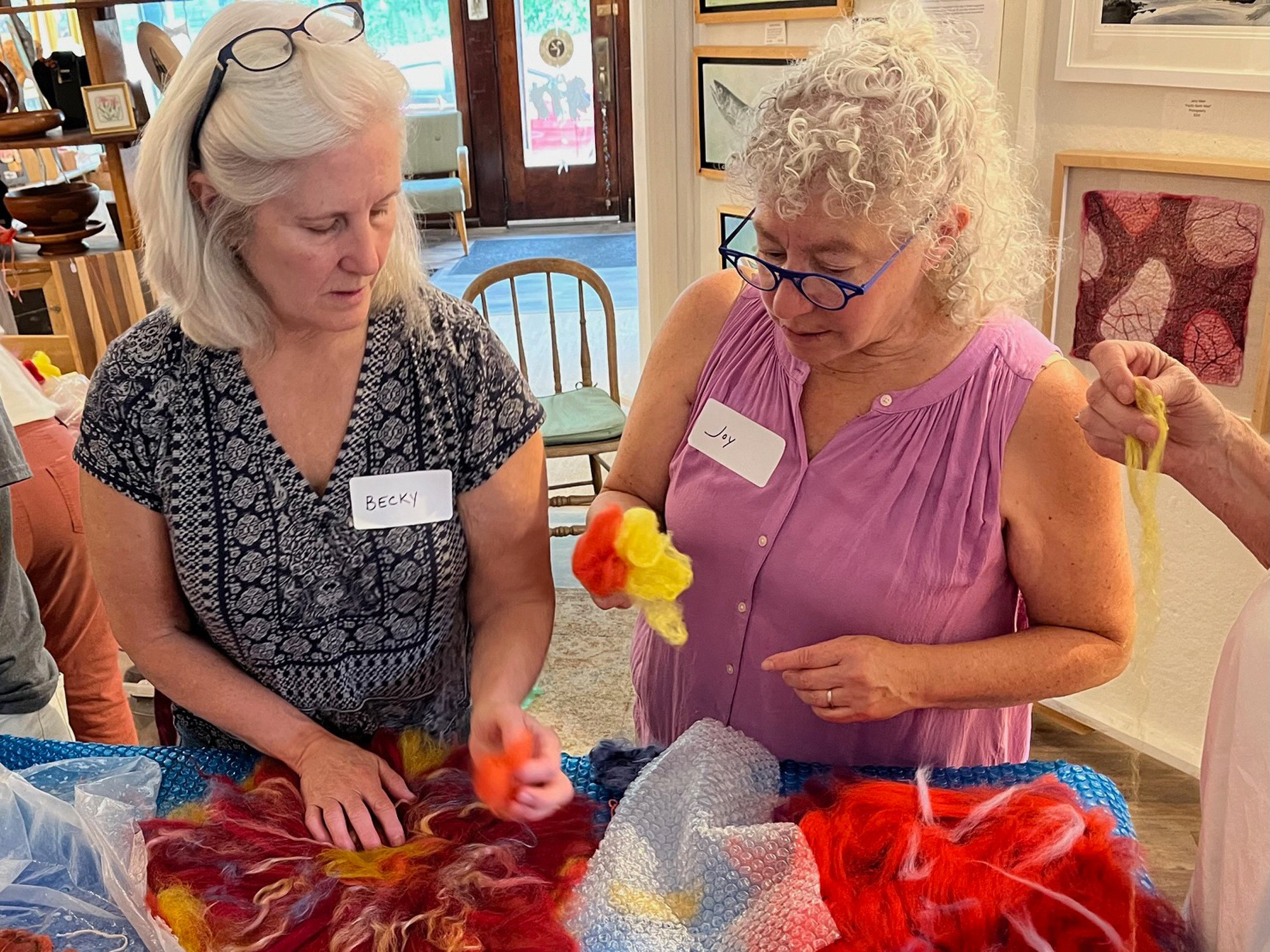 A workshop participant and the instructor look at wool for the felted suns.