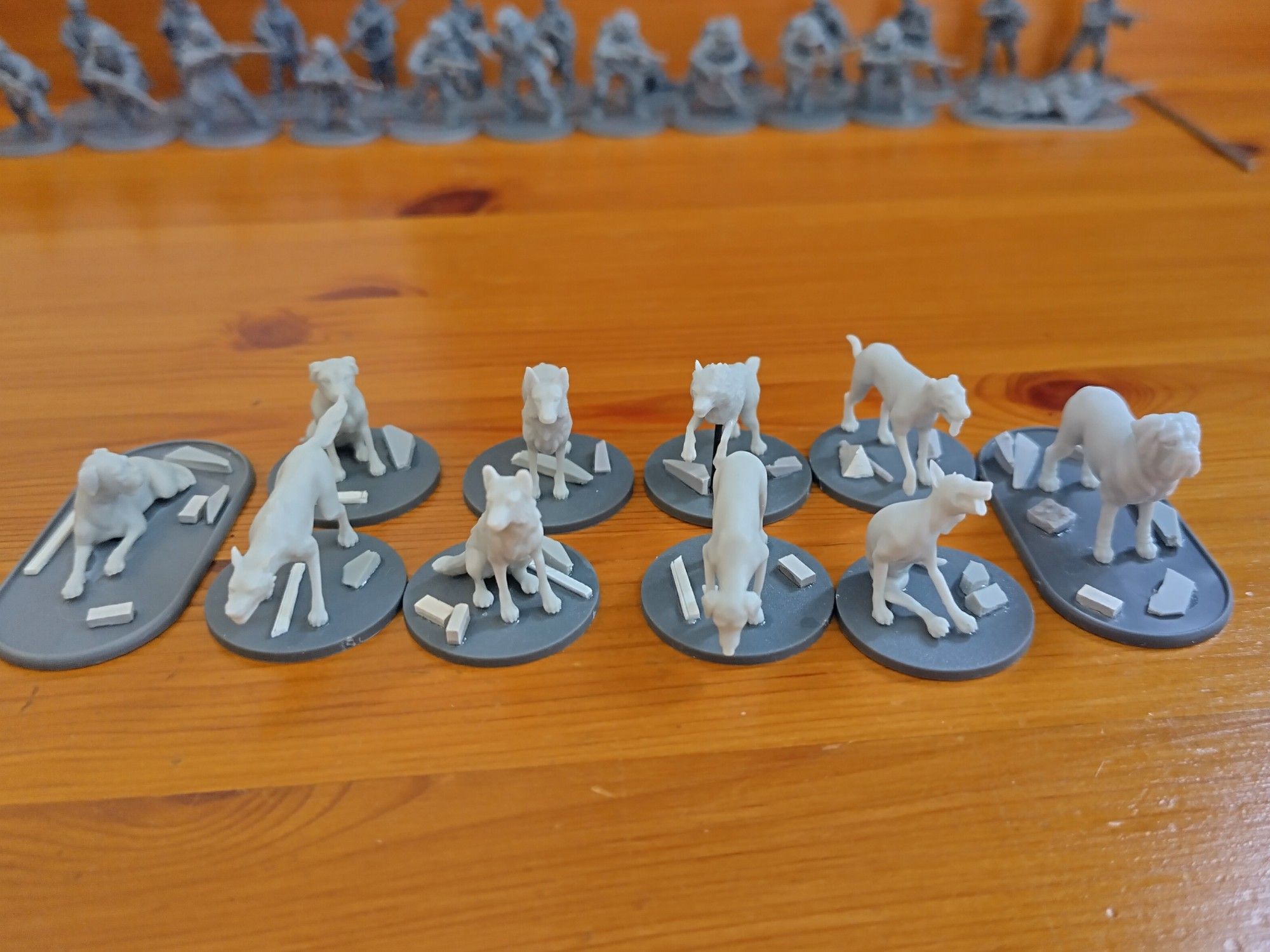 Unpainted grey dog miniatures on a wooden desk top