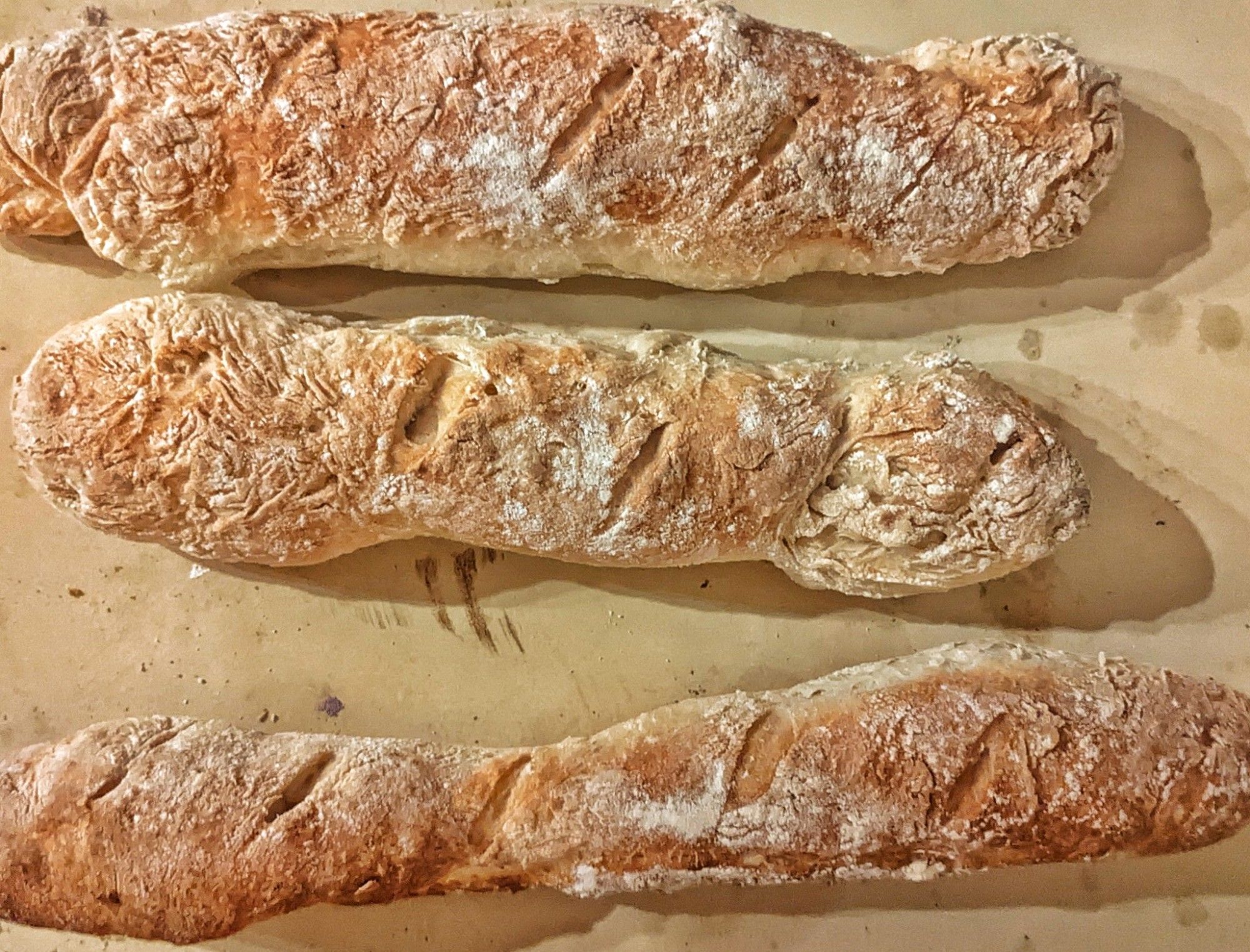 Images of three homemade baguettes fresh out of the oven.