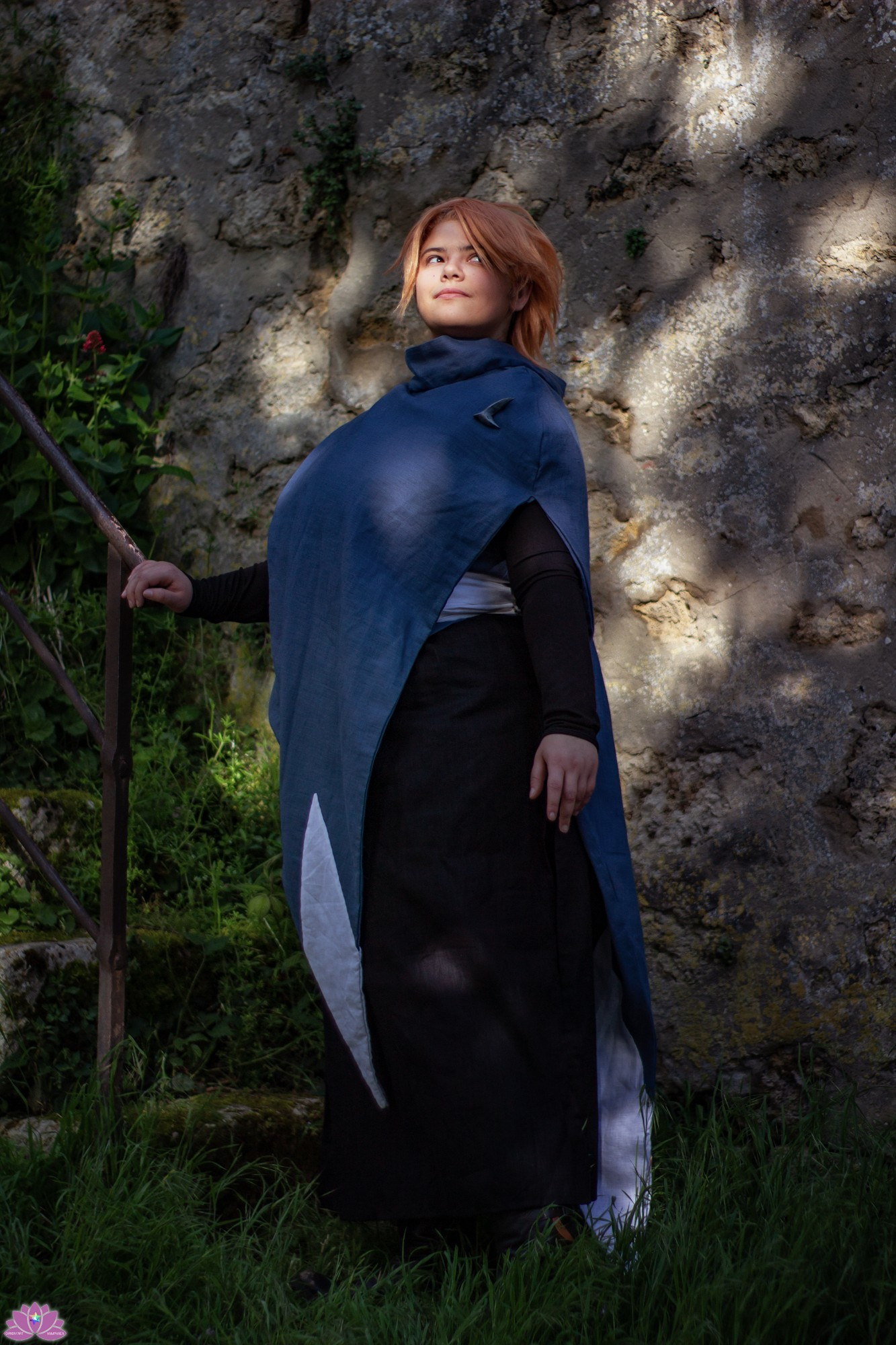 Illiane cosplaying as Sypha Belnades from the Castlevania Netflix show, chilling and smiling in a medieval city 