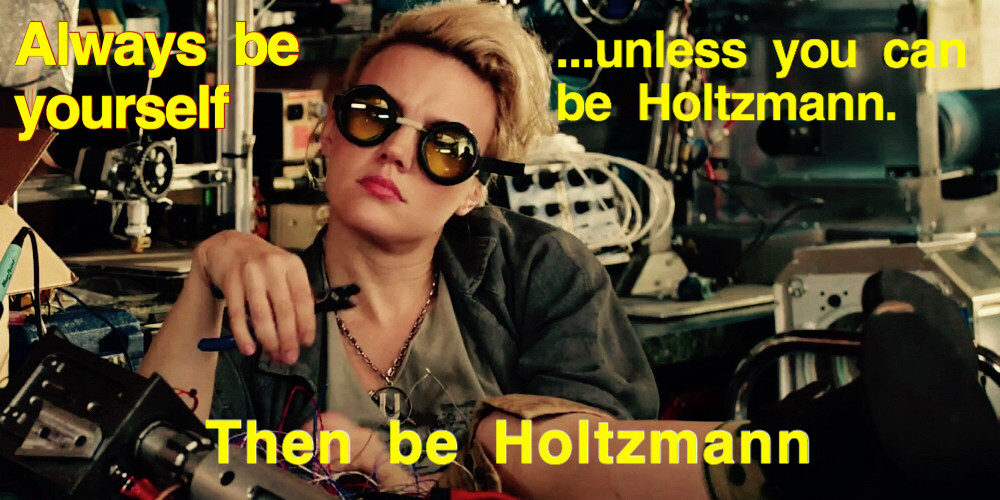 Picture of Kate McKinnon as her character Jillian Holtzmann, seated amongst a huge assortment of strange electronic gizmos and twiddling a wire cutter. Her clothes are shop appropriate and she’s wearing a pair of bugeye safety goggles. 

Text reads :

“Always be yourself”

“…unless you can be Holtzmann.”

“Then be Holtzmann”