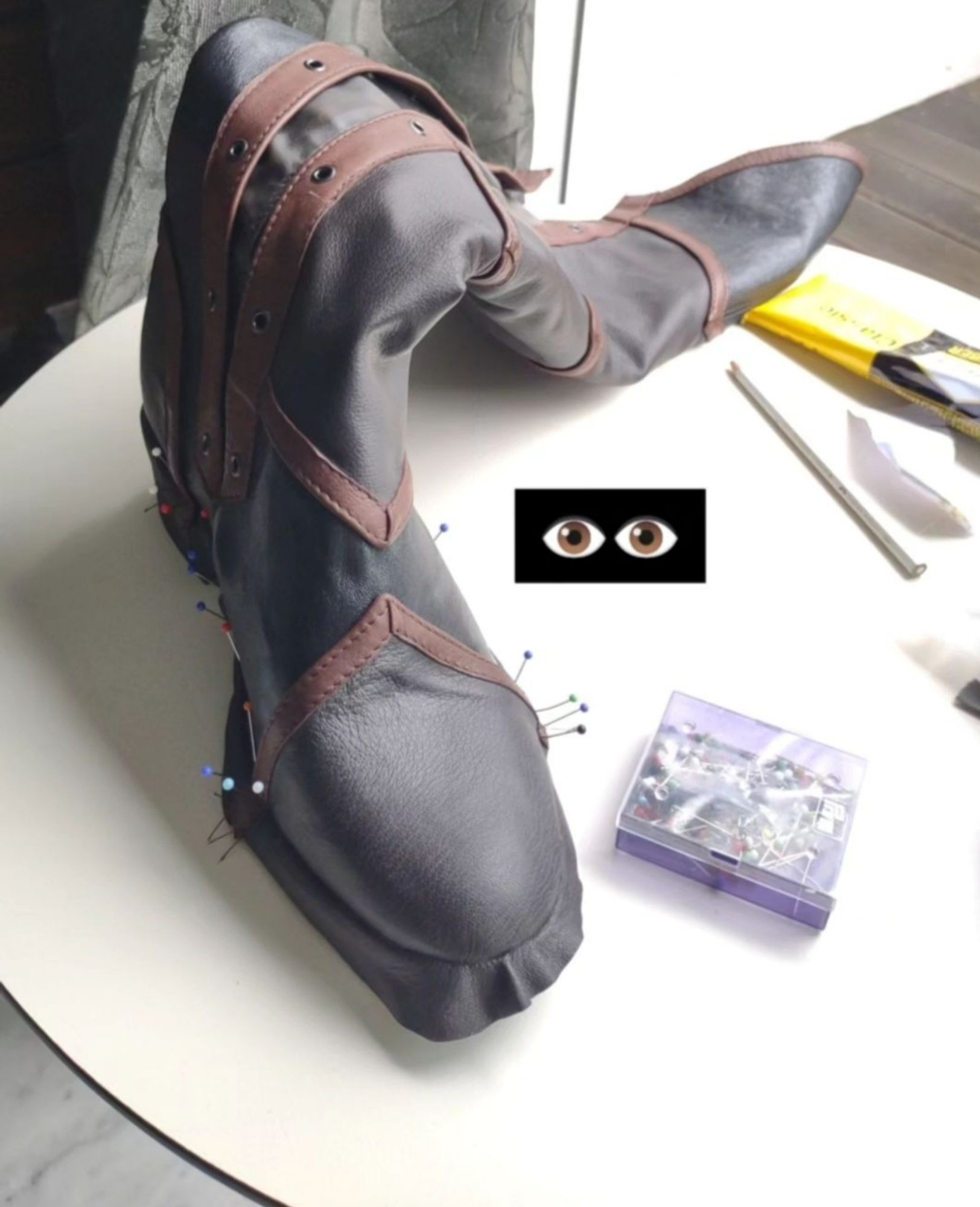 Text: "👁️👁️" boot cover being glued down on the base boots, pins sticking out the sides