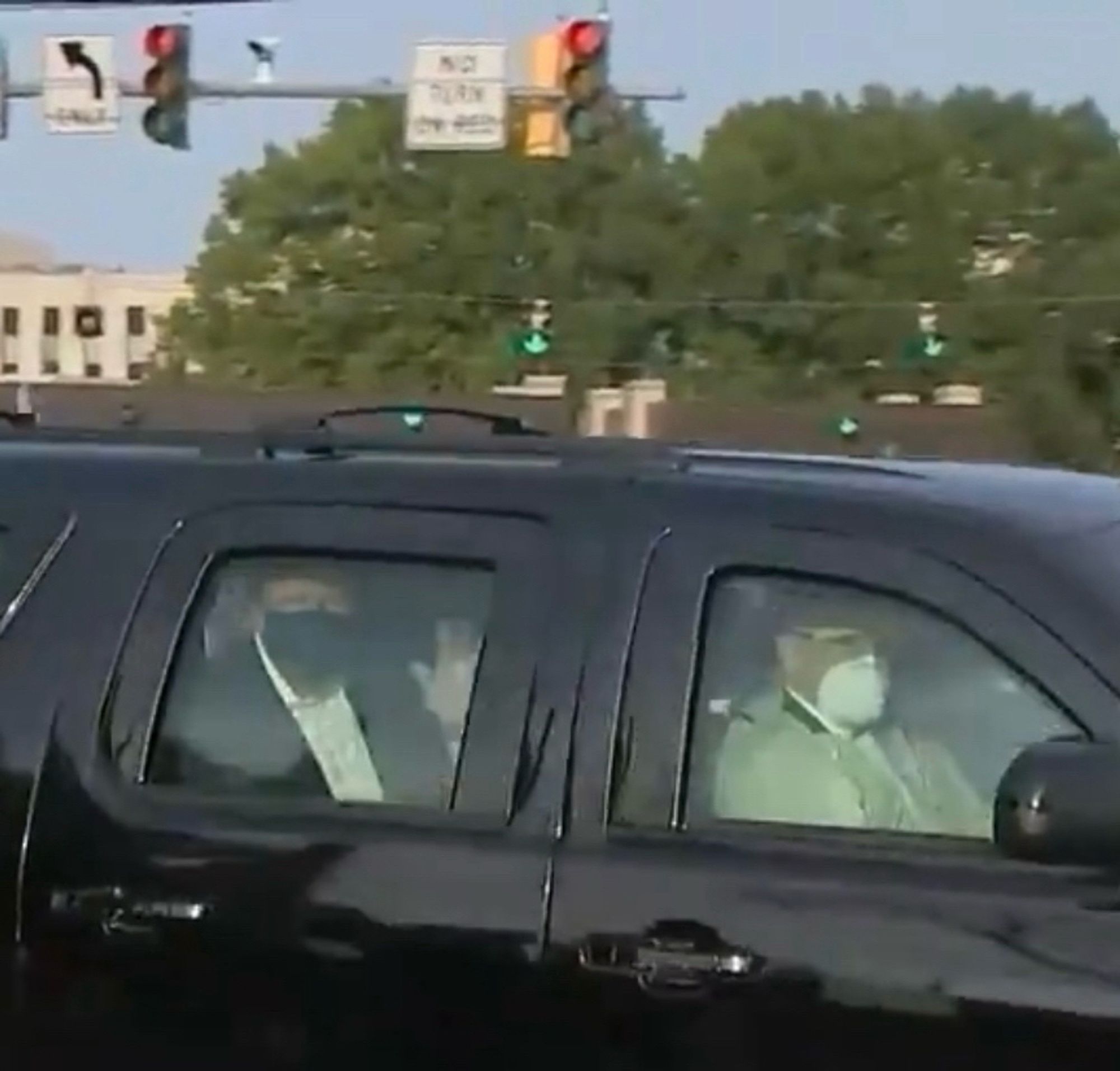 Trump waves from the backseat. A Secret Service driver and agent in the front seat wear facemasks