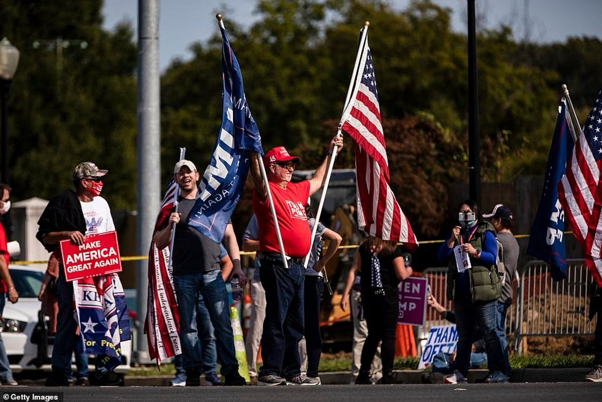 A handful of Trump supporters waving flags outside Walter Reed