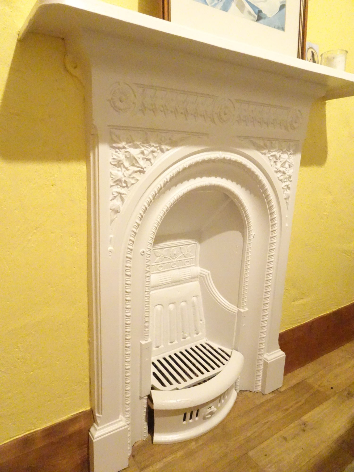 Gorgeous old white iron fireplace against the yellow wall. This is in your bedroom.