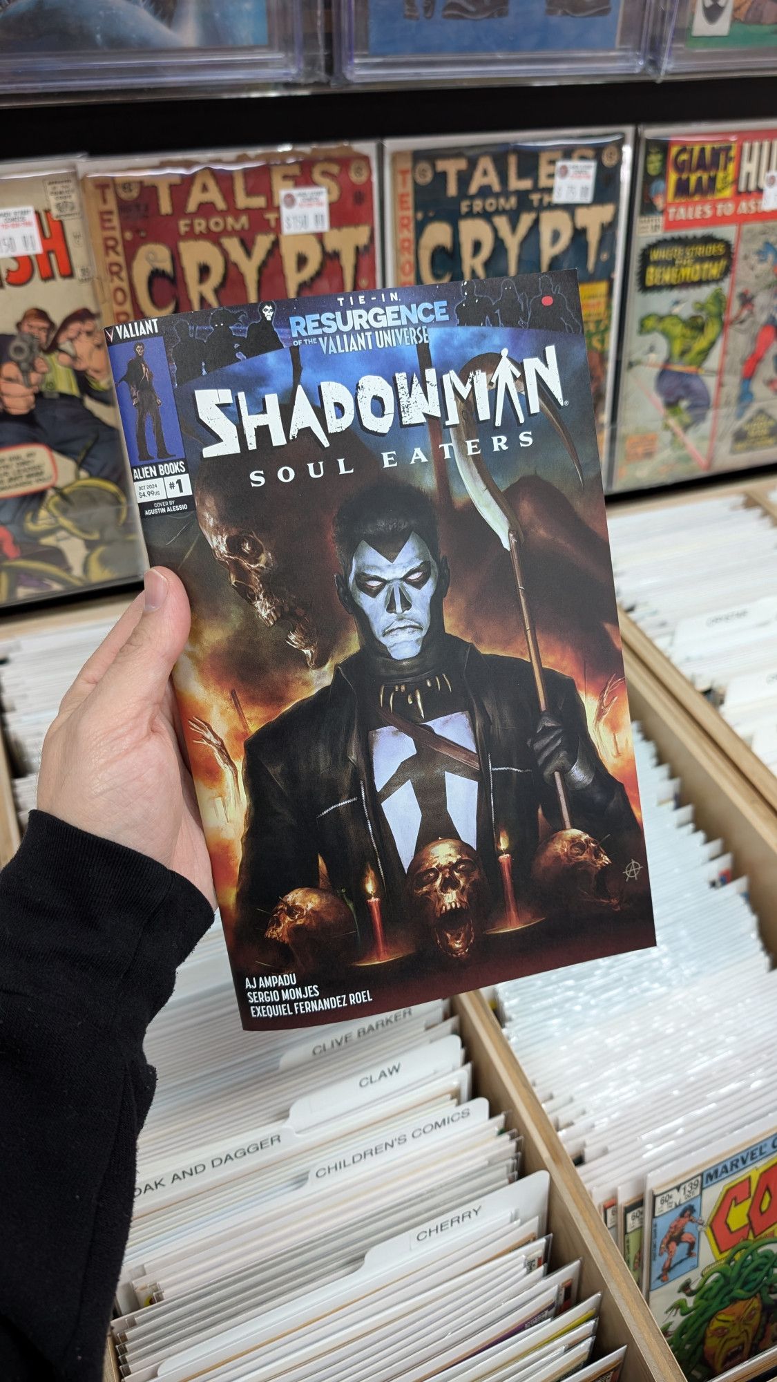 A hand holds up a comic book called Shadowman Soul Eaters above a back issue bin in a comic book store.