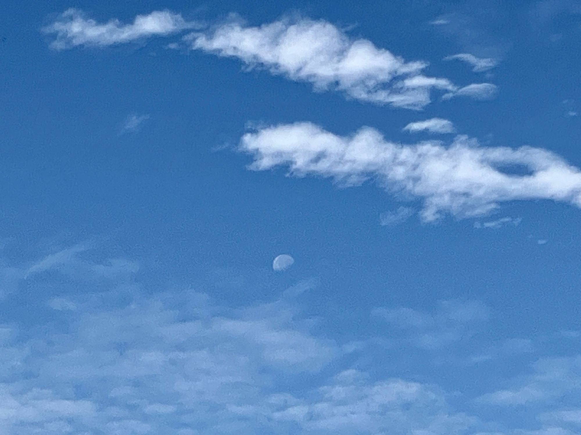 A closer view of a waning moon in a pale blue sky just before the white clouds enveloped it as it goes to set on the first day of fall.