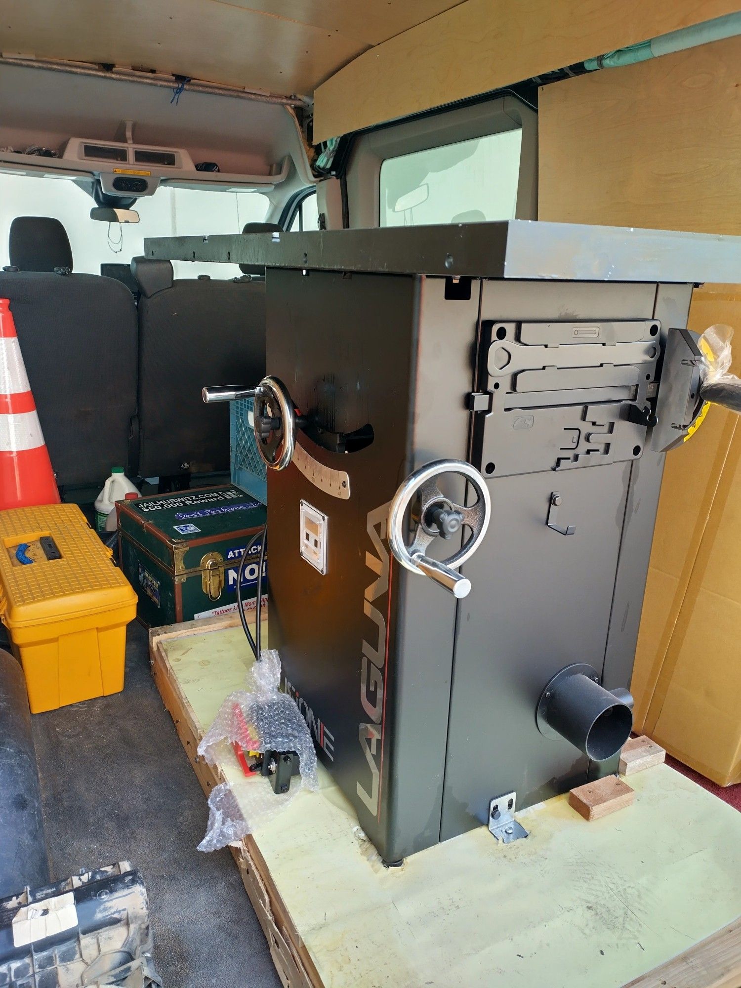 A cabinet table saw sitting on a pallet inside of a van