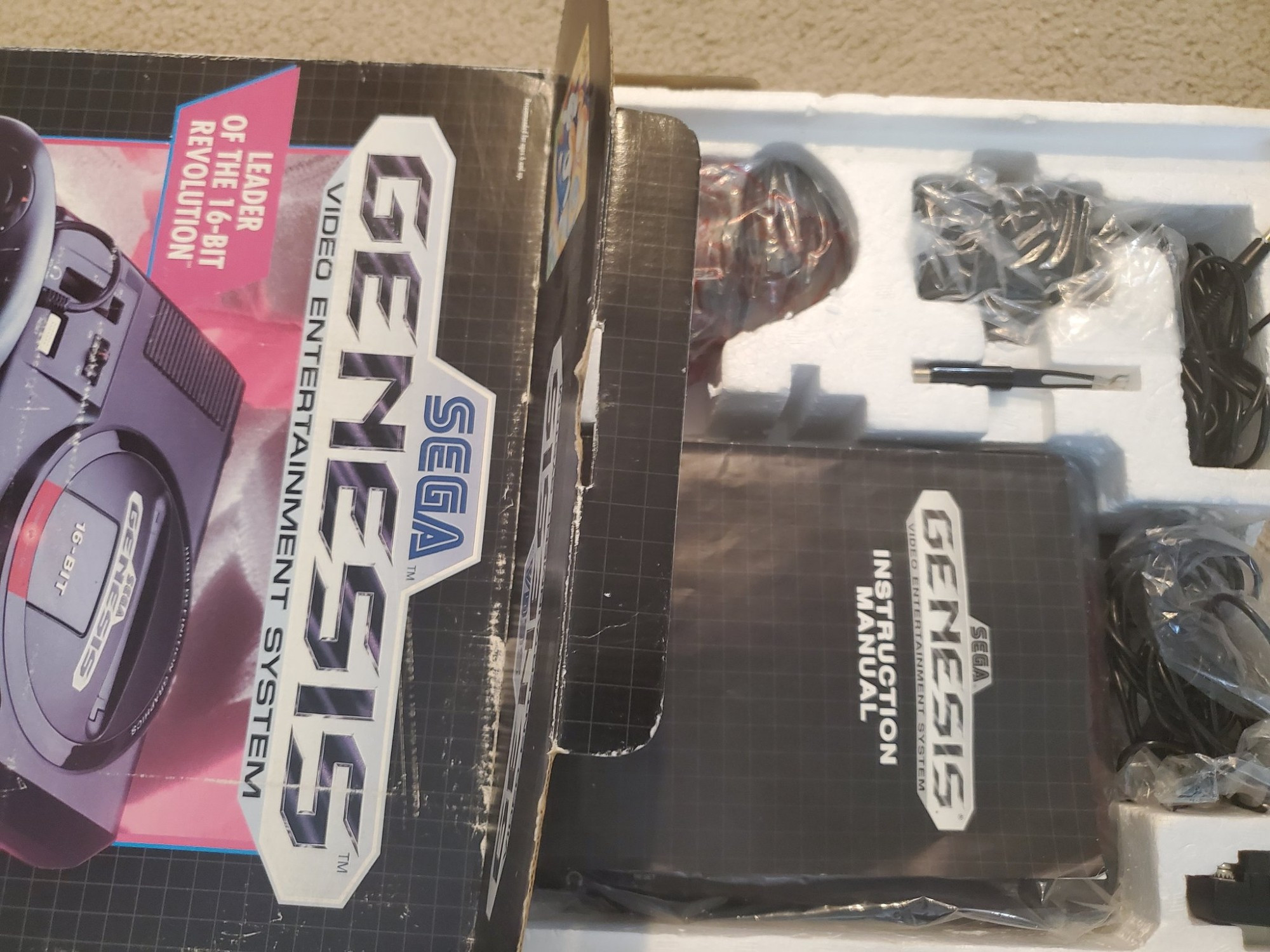 Opened Sega Genesis box showing the manual and parts