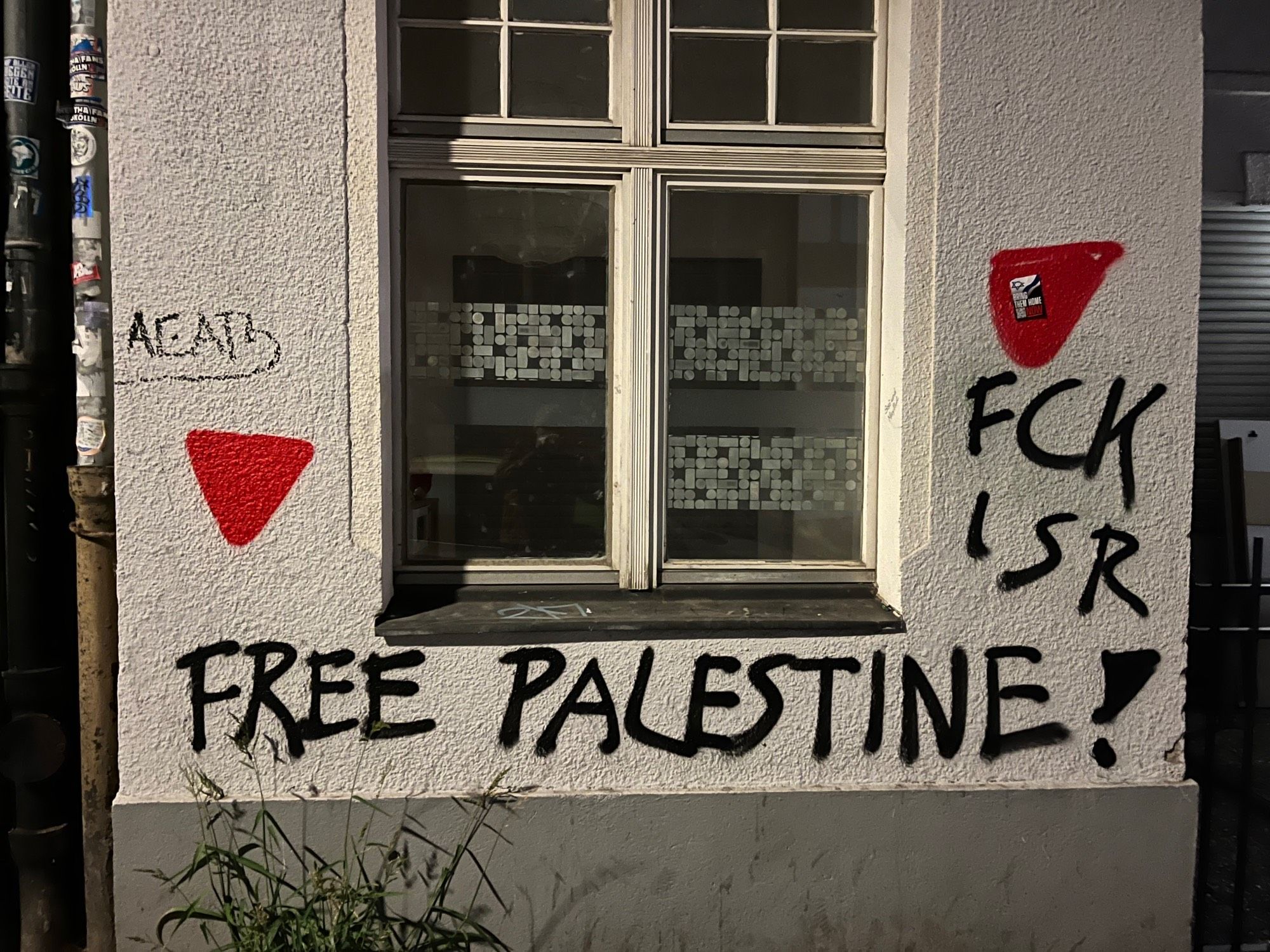 Eine Hauswand mit Fenster, darauf zwei rote Hamasdreiecke und die Slogans „Free Palestine!“ und „FCK ISR“