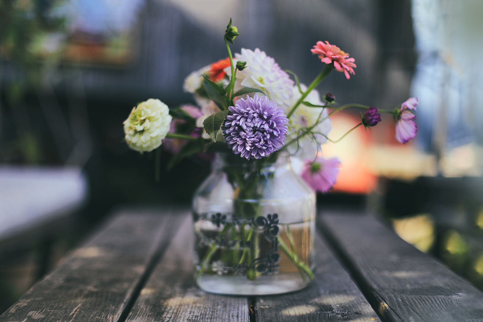 Ein Blumenstrauß in einer Glasvase auf einem Holztisch. Die Blumen sind aus dem Bauerngarten des Hättelihofes.