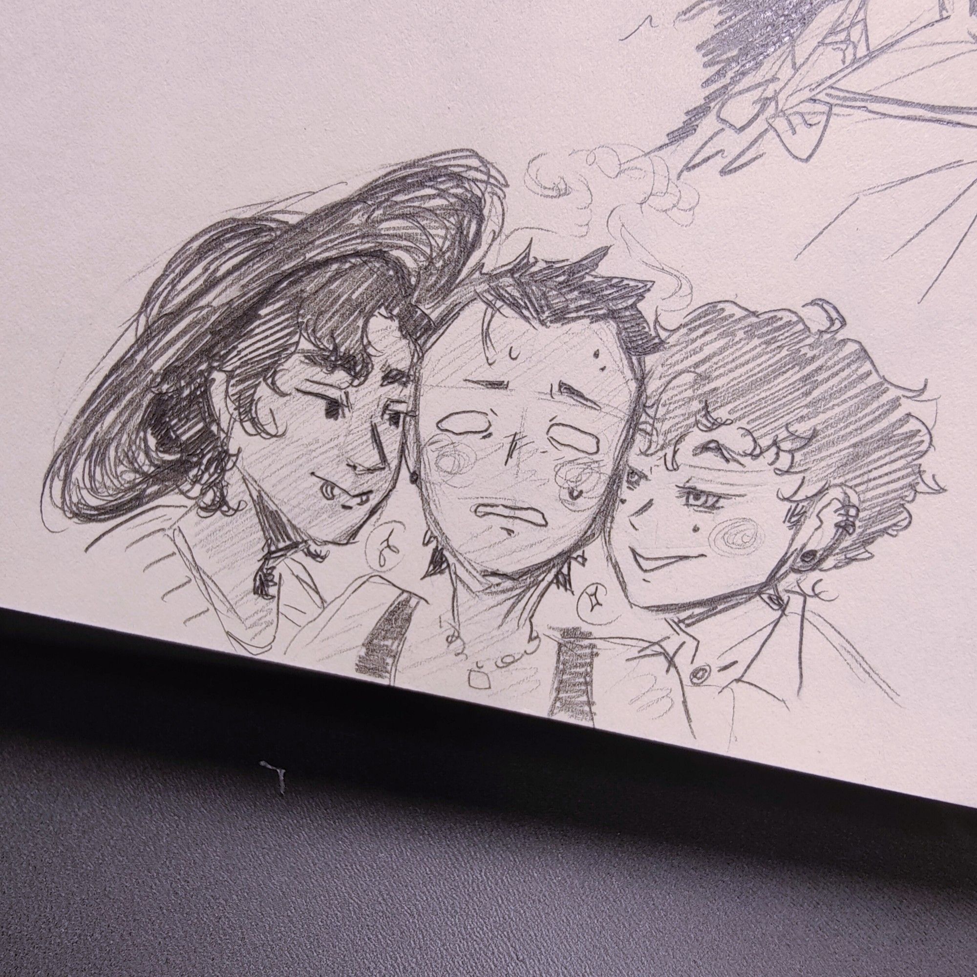 A pencil sketch featuring three of my OCs, Damião, Aki and Noah. 
Damião has dark hair and dark skin, and he has two lip piercings and wears a dark brimmed hat. He's on the left of the pic, leaning towards Aki who's positioned in the middle.
Aki has dark pushed back hair and tanned skin, and he's in the middle of other two guys, visibly flustered and unsure how to be.
Noah has red hair (not shown in the black and white sketch) and beauty marks under each eye. He's also leaning in towards Aki, with a bit of a mischievous grin on his face.