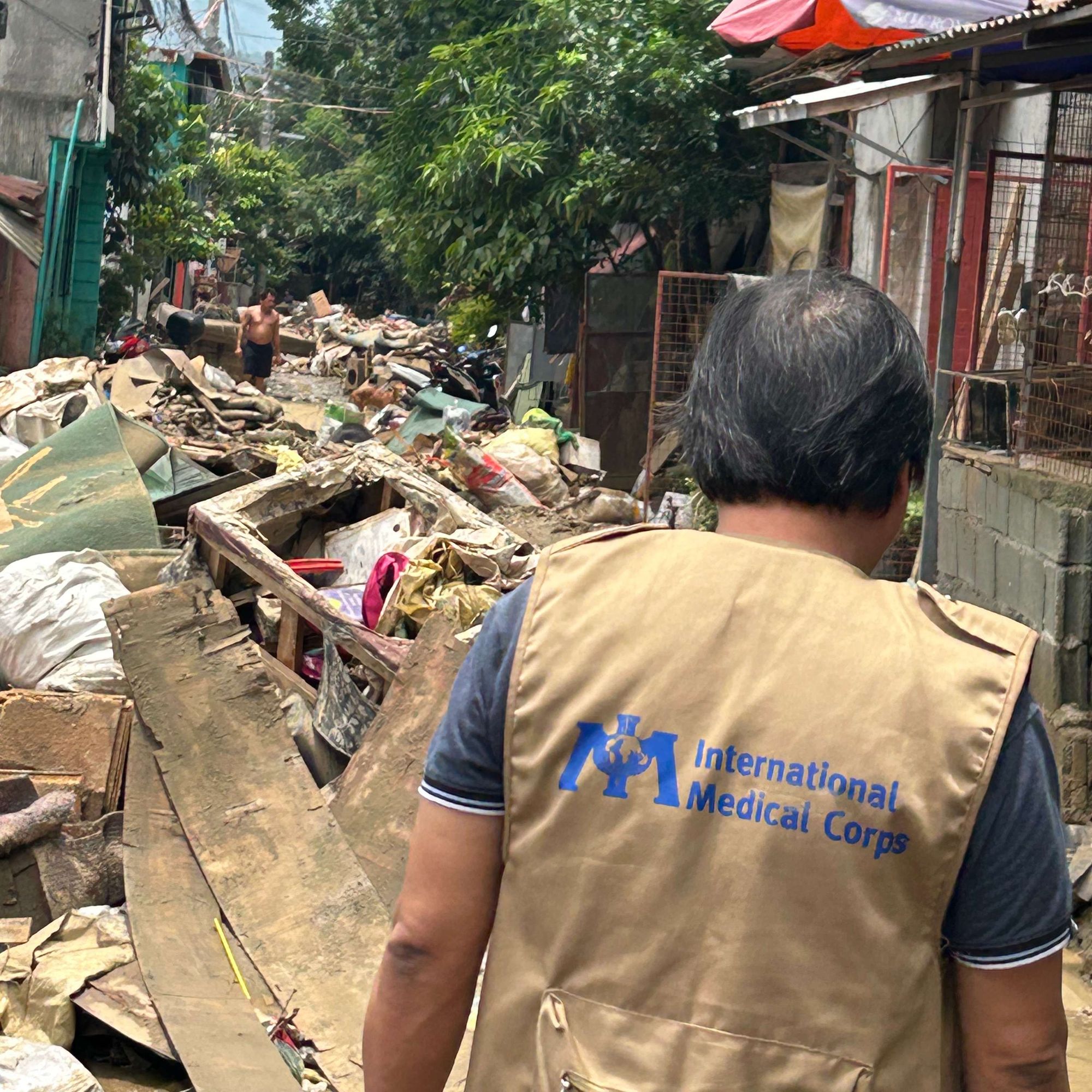 International Medical Corps staff member standing in front of destruction left by Typhoon Gaemi.