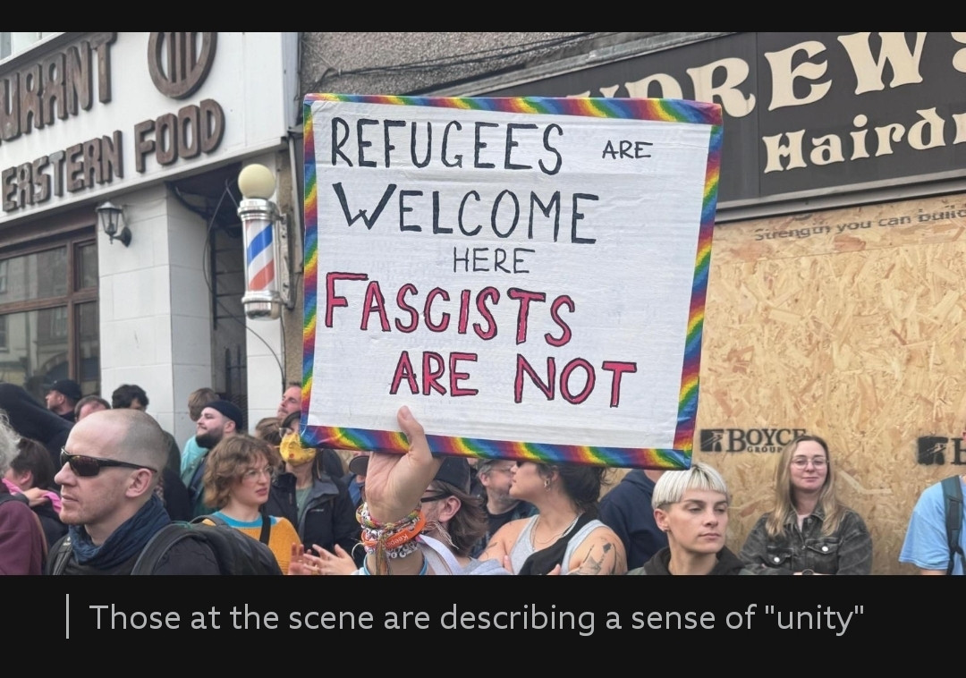 Evander holding up their banner in a Bristol street full of anti-fascist marchers. You can just see their hand. Photo on the BBC News website.