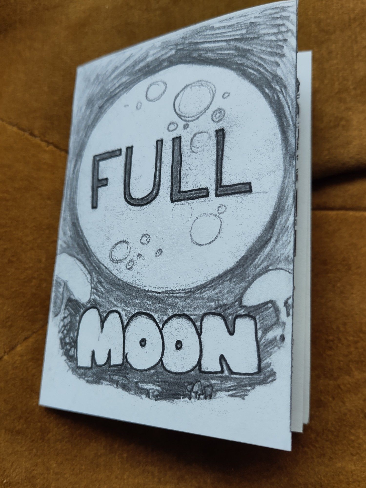 A mini zine titled Full Moon with a big moon on the background and mushrooms growing across the bottom