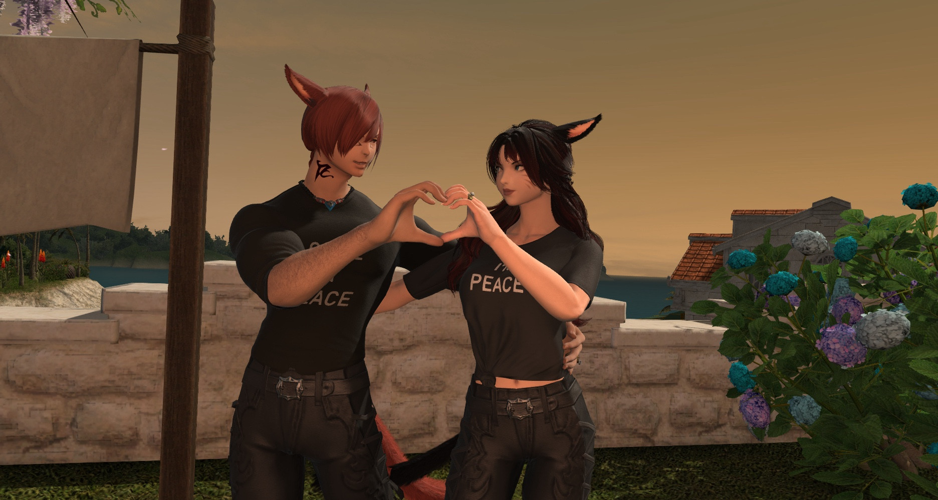 K’yalwenn and G’raha are wearing the same t-shirts from the previous picture, but are holding their hands together to make a heart shape.