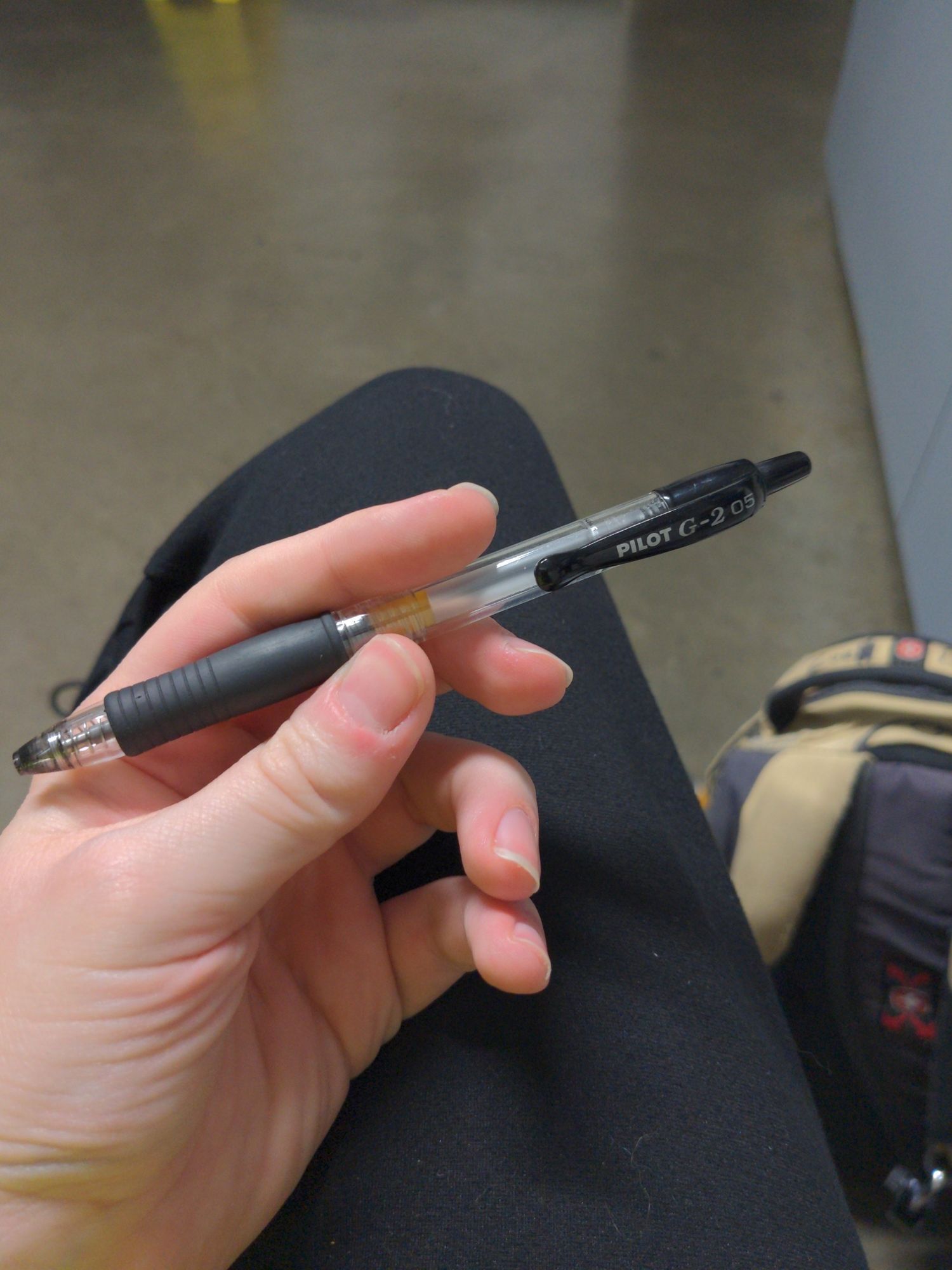 Zoe daintily holding a Pilot G-2 5 Bore black pen, the everyman's pen. It's been well used.