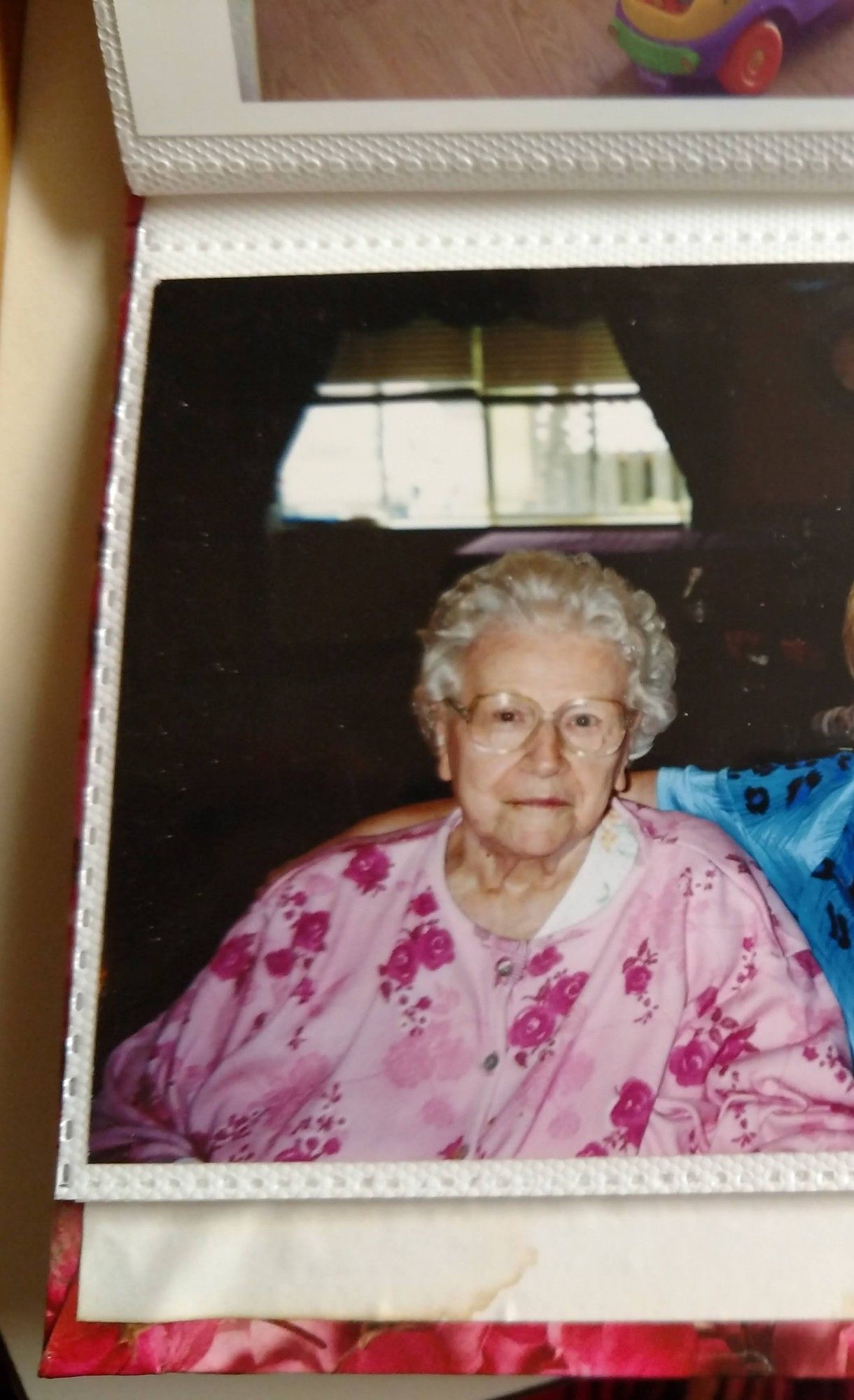 My grandma at about 96 years old. She has thick white carefully curled hair, light-framed glasses, and is wearing a pink flowered dressing gown. Her face is mostly unwrinkled. The stroke took her speech but not her salty personality or her careful attention to her appearance. There was a jar of Nivea cold cream on her nightstand even then.