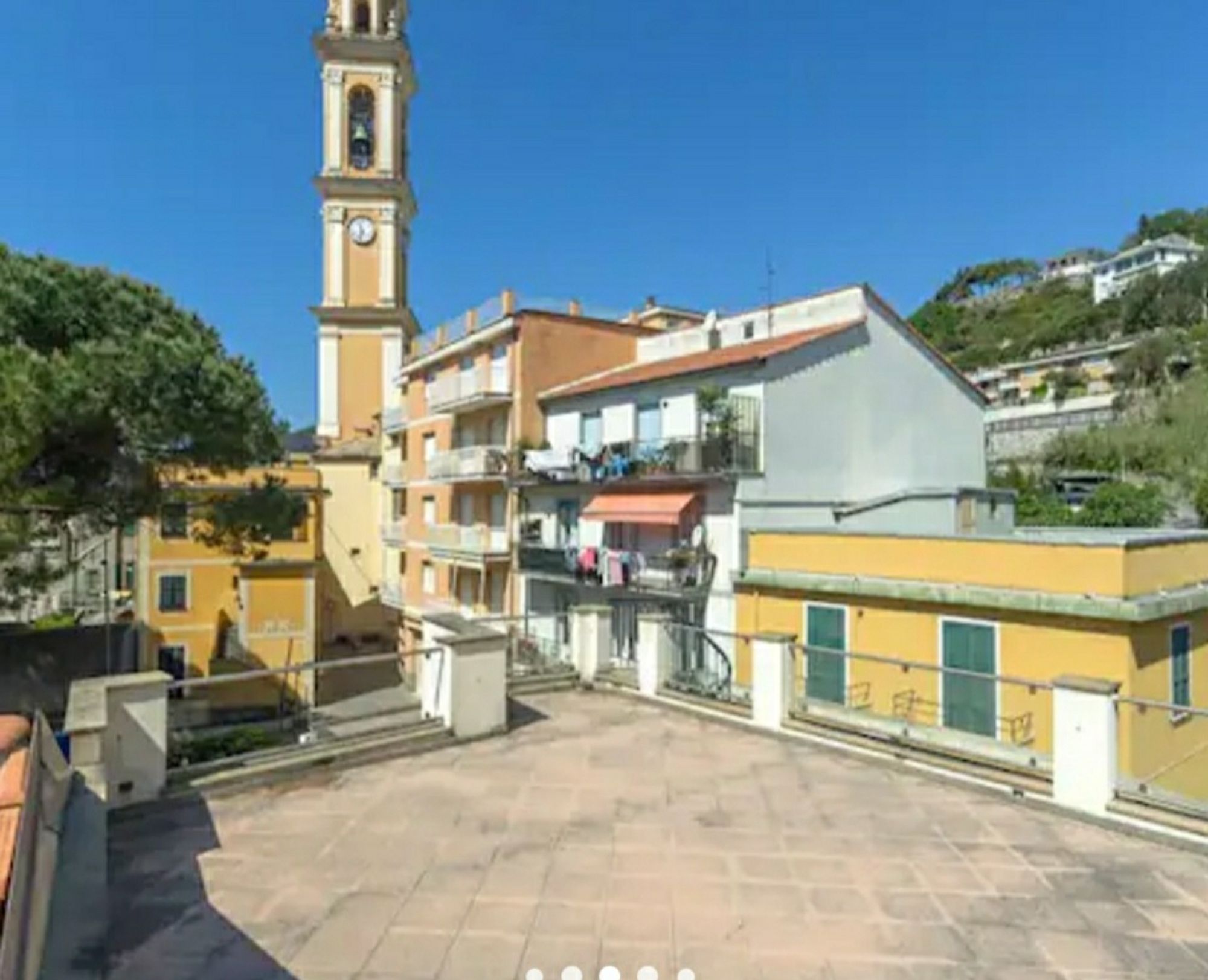 Katalogbild einer Dachterrasse in der Sonne, dahinter Häuser einer Altstadtgasse und ein Kirchturm, der Gesamteindruck ist nicht uneinladend.