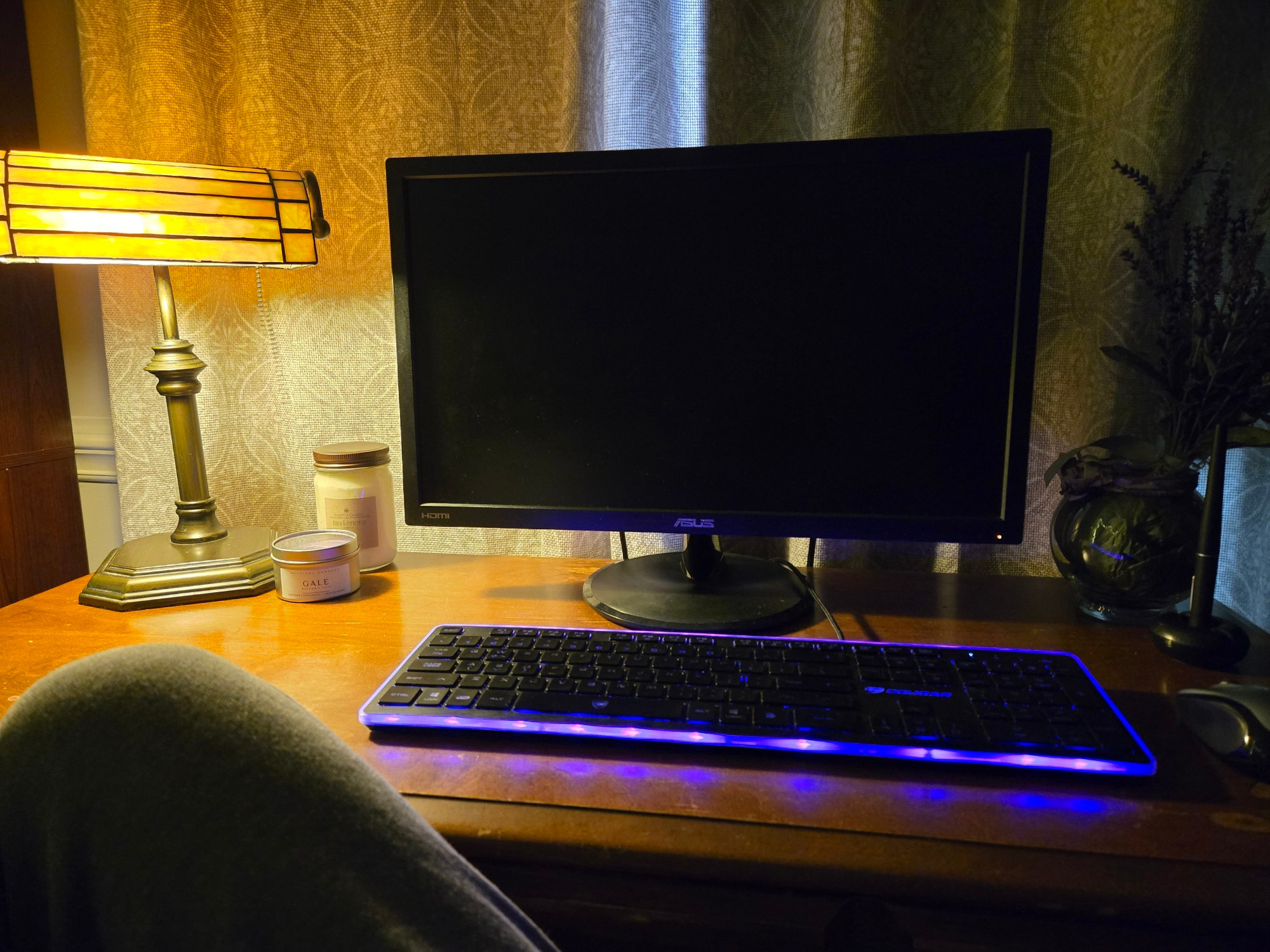 My desk with an old-fashioned lamp for ambiance, two candles, a keyboard with a purple backlight, and a little fake plant