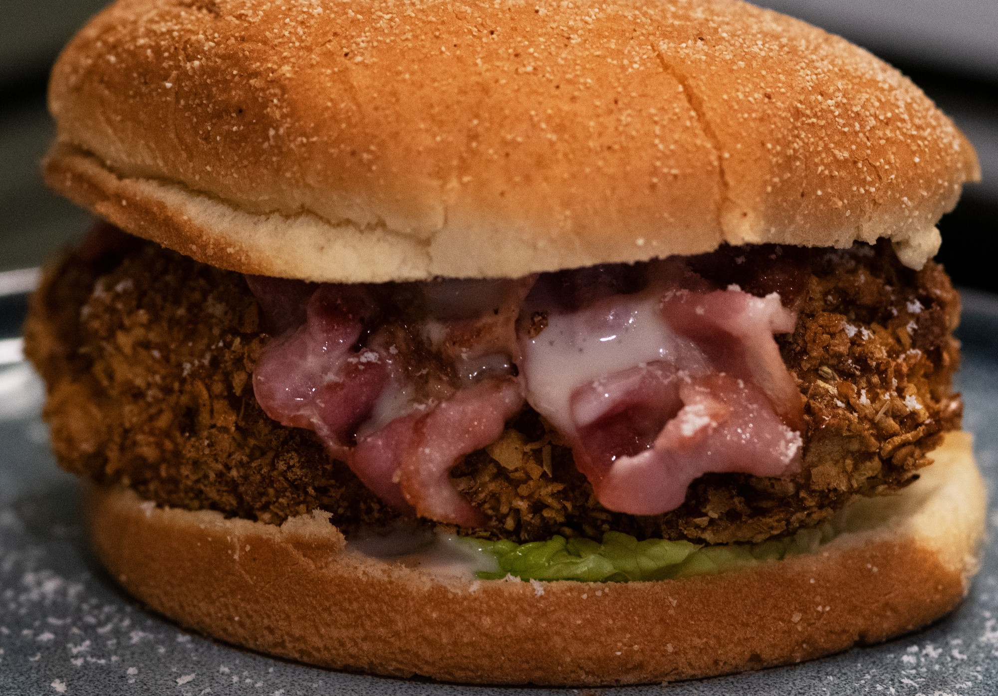 Crispy chicken in a burger bun with bacon rashers, lettuce and caesar dressing