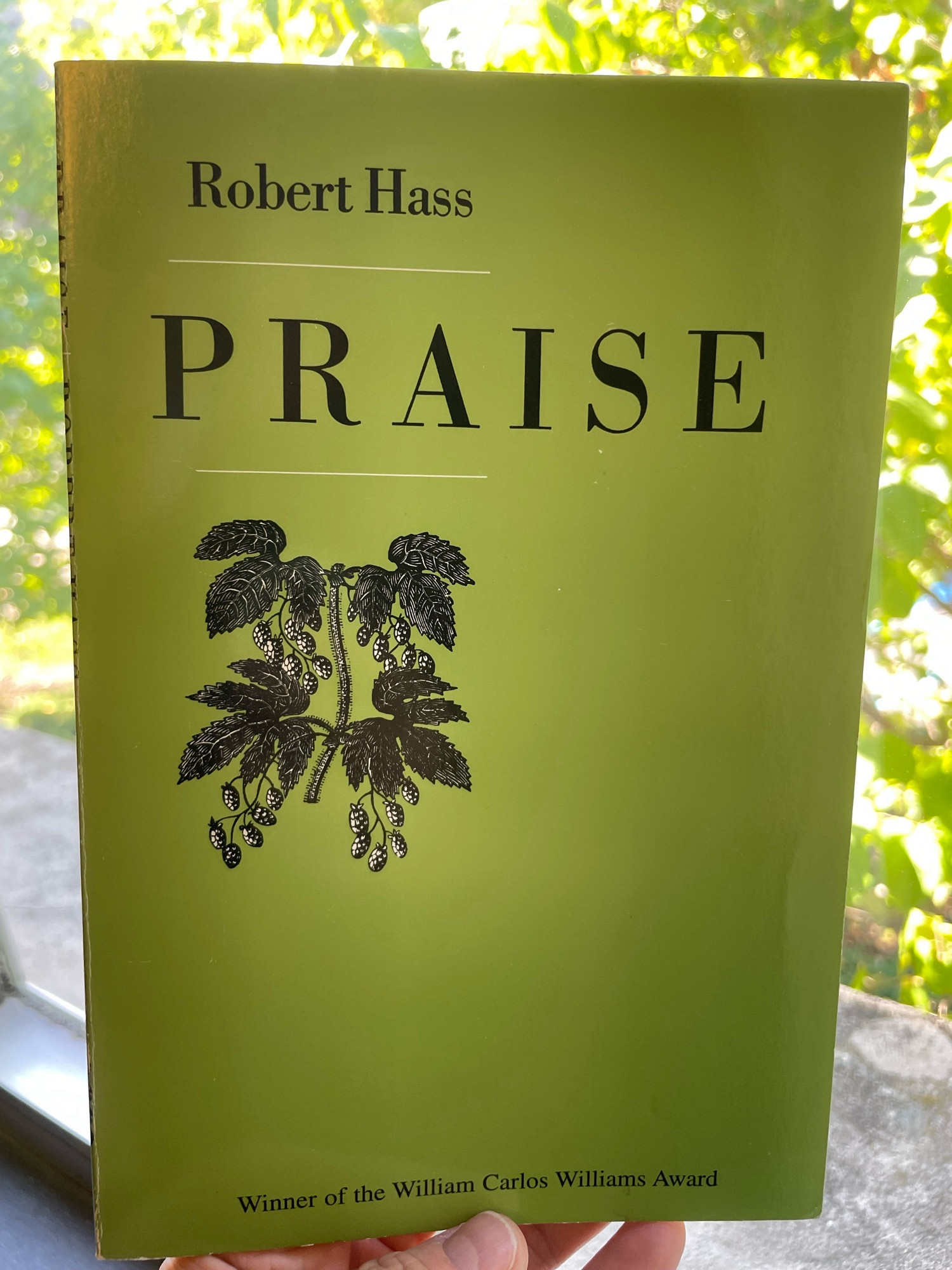 The green green cover Robert Hass’s book PRAISE, winner of the William Carlos Williams Award, with a little engraving of blackberries filling a small portion of the larger plane of solid green. Bright green leaves in the background.