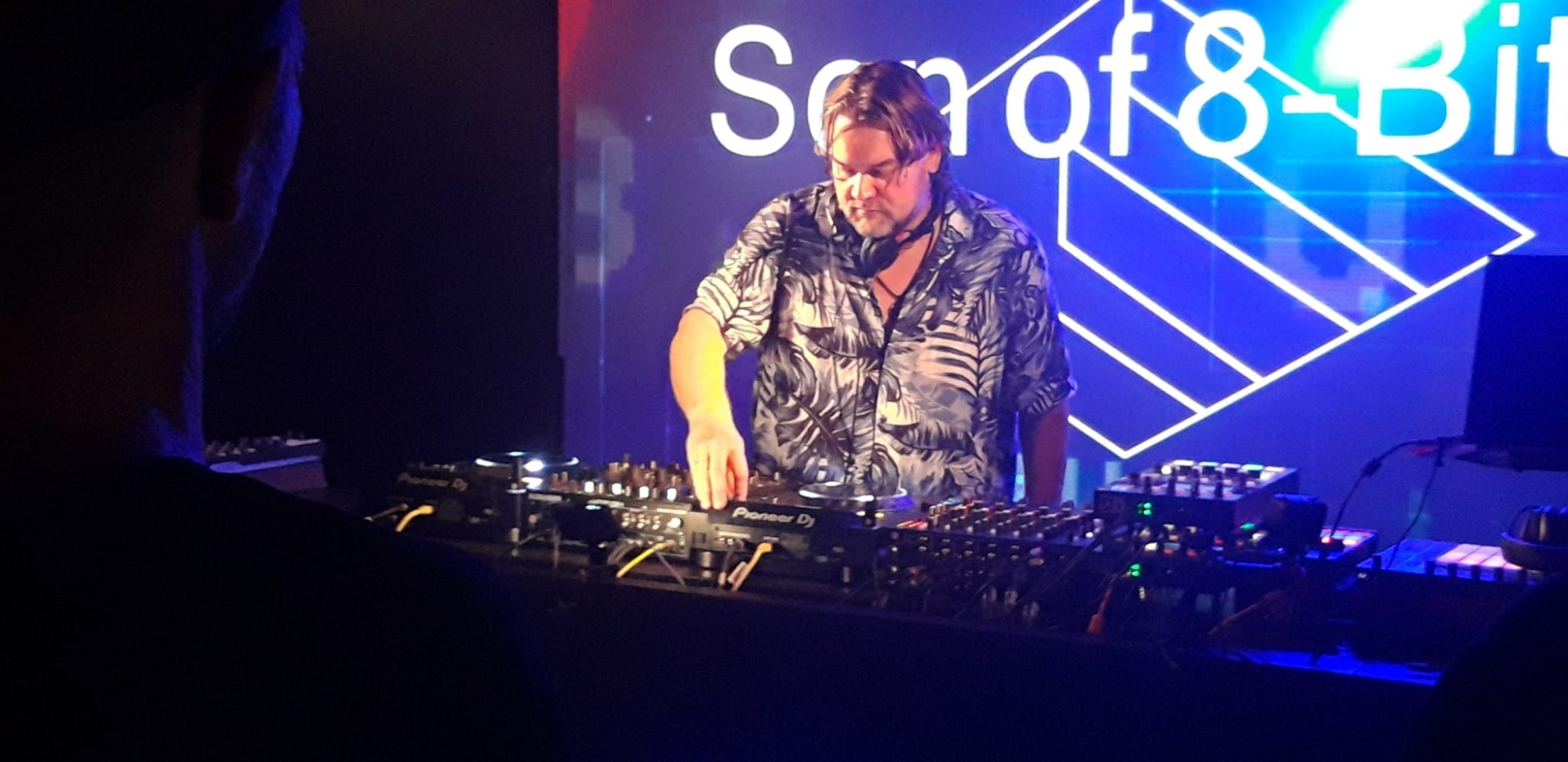 Me, in a Hawaii shirt, performing at Bassment Amsterdam diligently mixing behind a set of Pioneer CDJ2000 nexus' and a Allen & Heath Xone DB4.